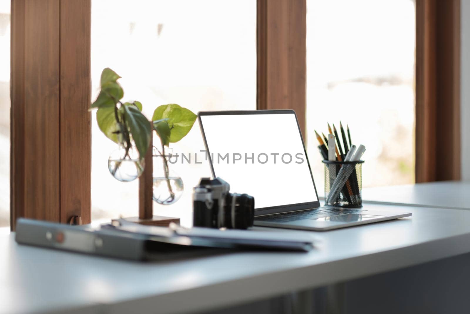 Close up view of laptop computer with blank white screen with office supplies in modern office by nateemee