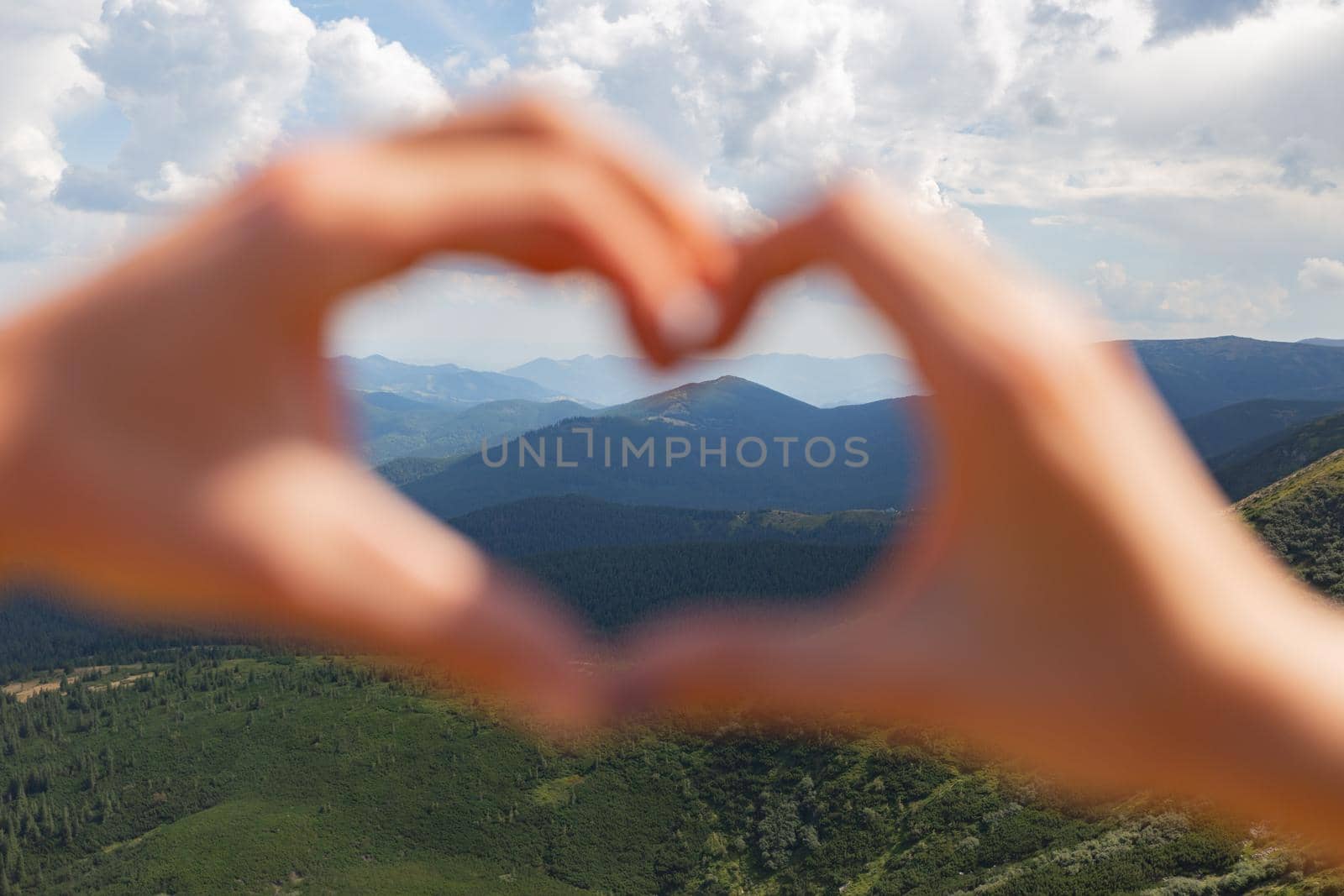 The Couple Make a Heart With Their Hands on the Background of the Sky by TrEKone