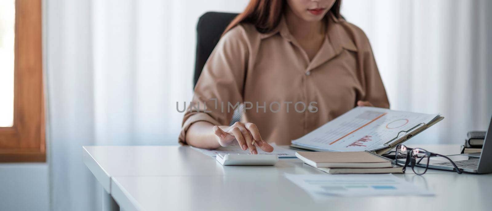 Business woman working in finance and accounting Analyze financial budget with calculator and paperwork in the office