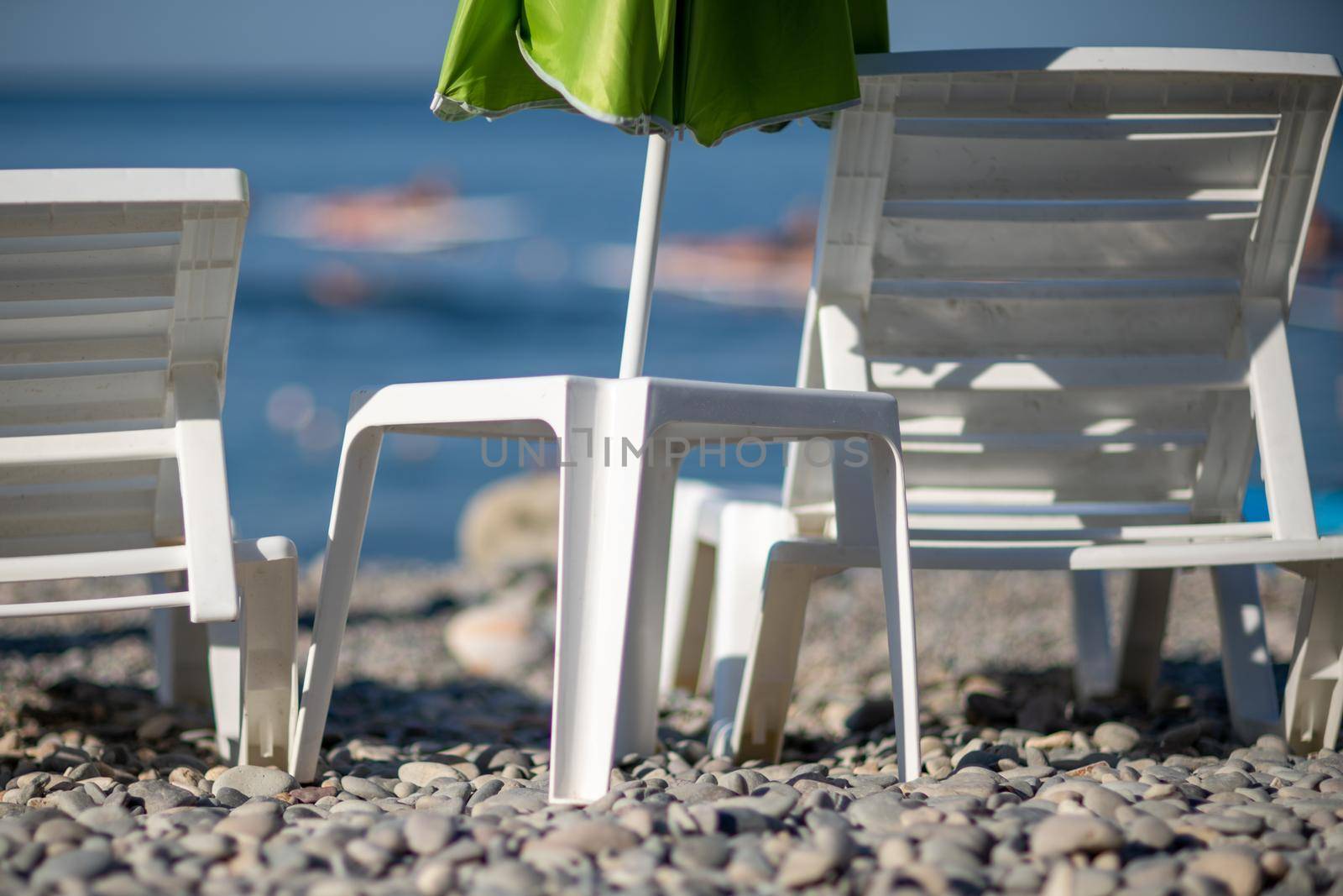 Several white sun loungers and an umbrella on a deserted beach. The perfect vacation concept. by Matiunina