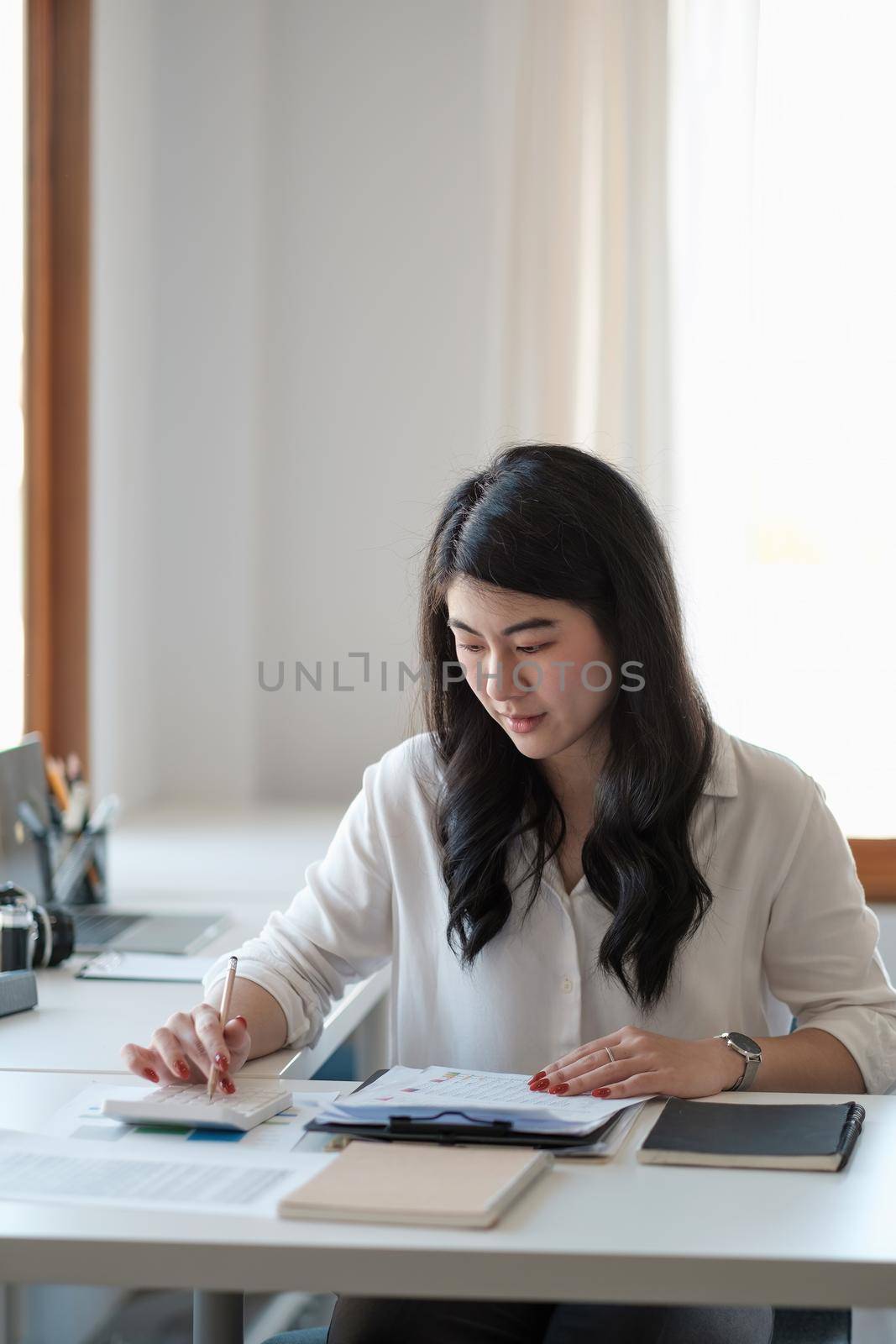 Portrait asian business woman working with calculator hand pointing graph discussion and analysis data charts and graphs.Business finances and accounting concept.