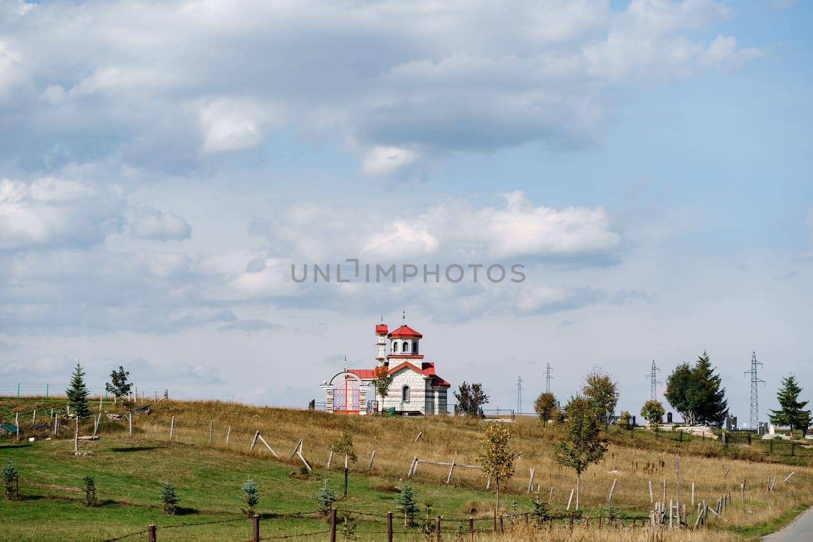 White brick church with red roof in the field. High quality photo