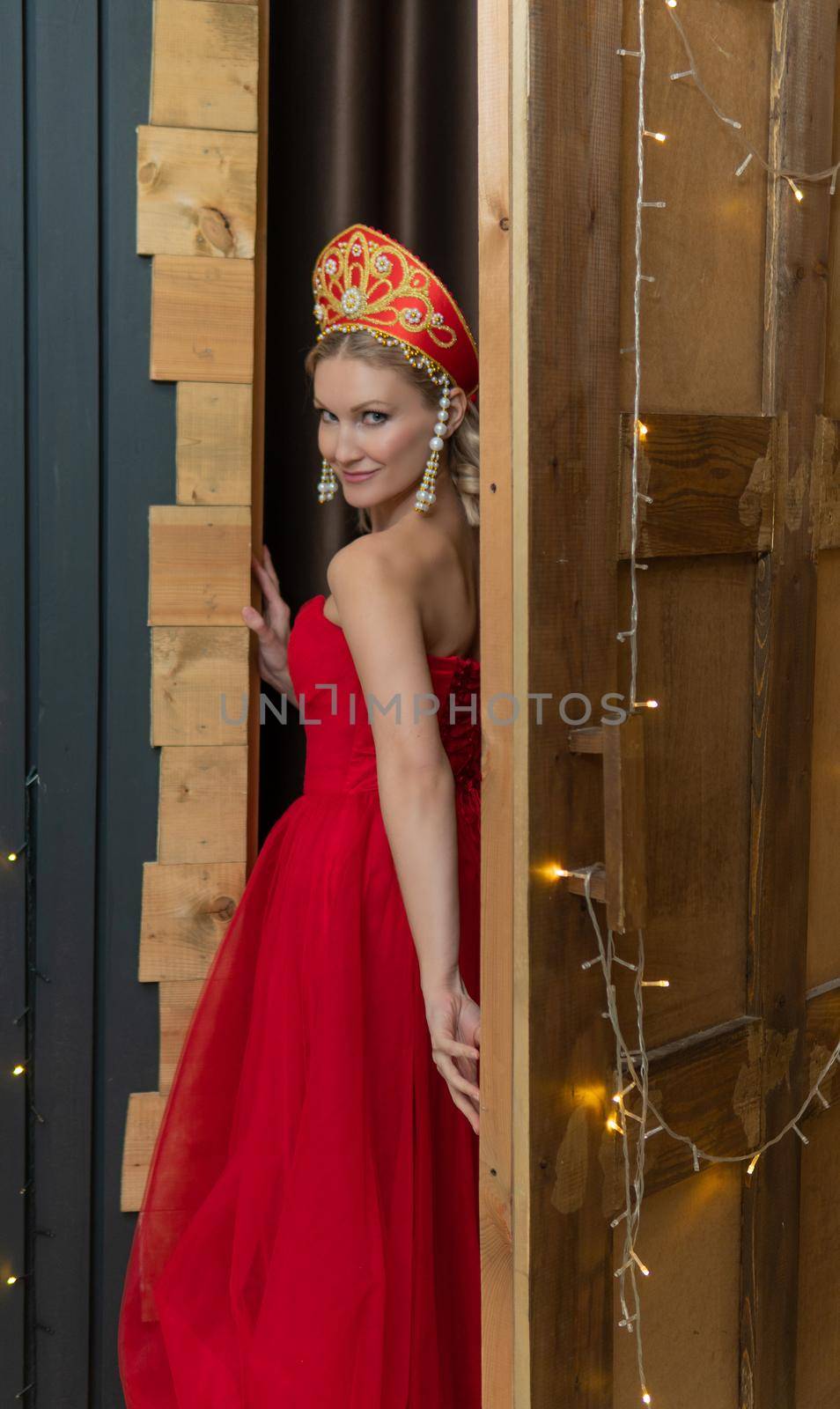 Russian girl in traditional kokoshnik clothes and red dress beautiful stands portrait culture red beautiful plait, In the afternoon fashion dress for girl old sarafan, attractive bread. Headwear ritual hat, stands in the doorway