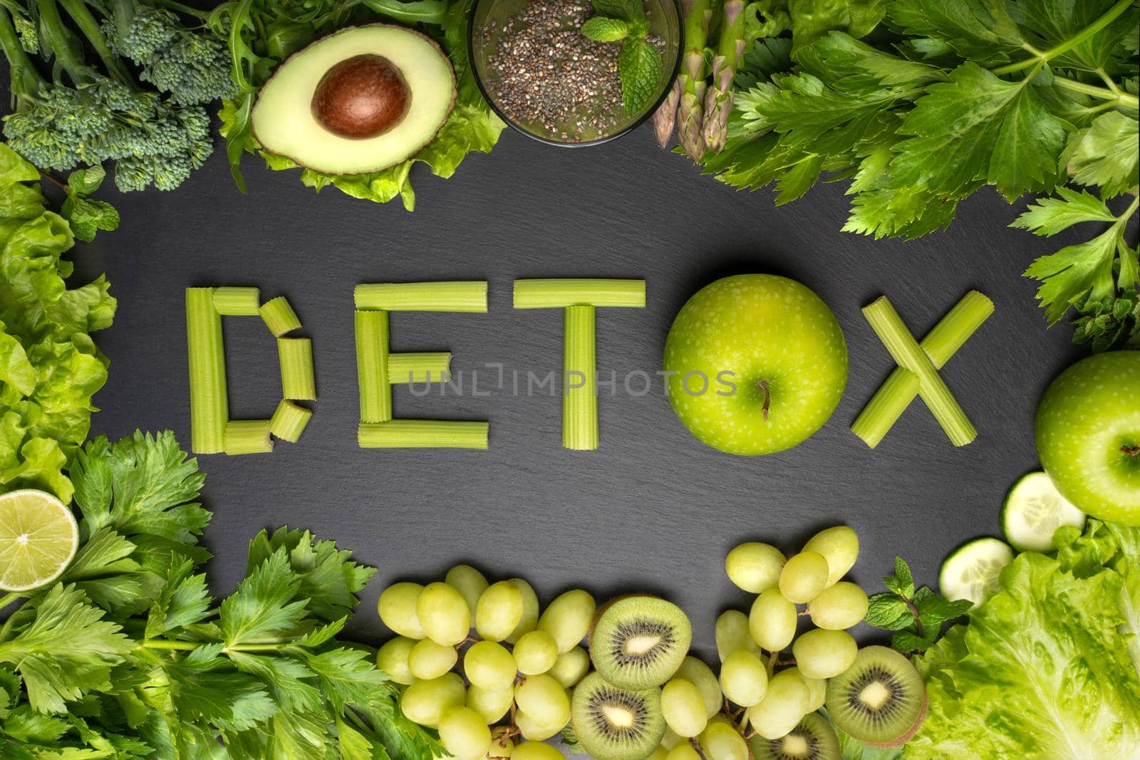 Top view of fresh green vegetables and fruits with word detox on a black background. Detox diet, clean and healthy eating. High quality photo