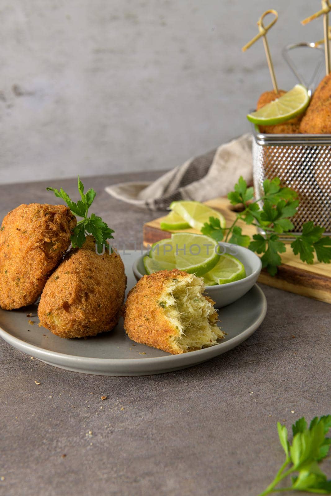 Meat croquets with rosemary leaves and lemons on wooden cutting board in a kitchen counter top.