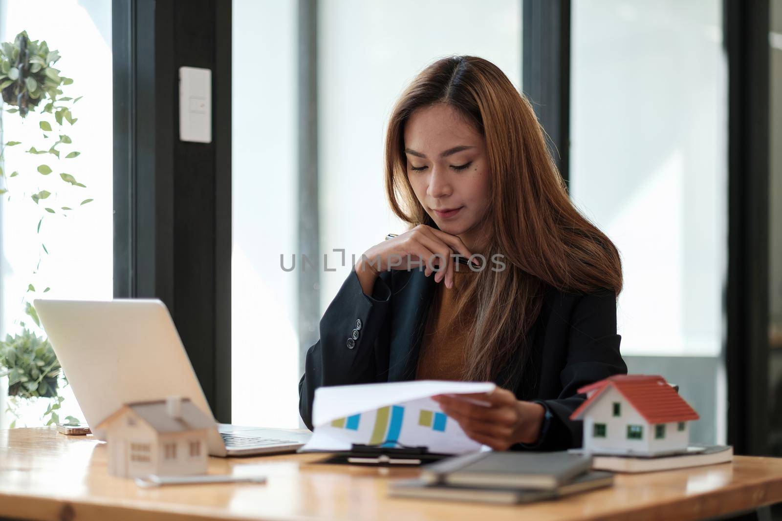 Asian business woman working for interest, taxes and profits to invest in real estate and home buying.