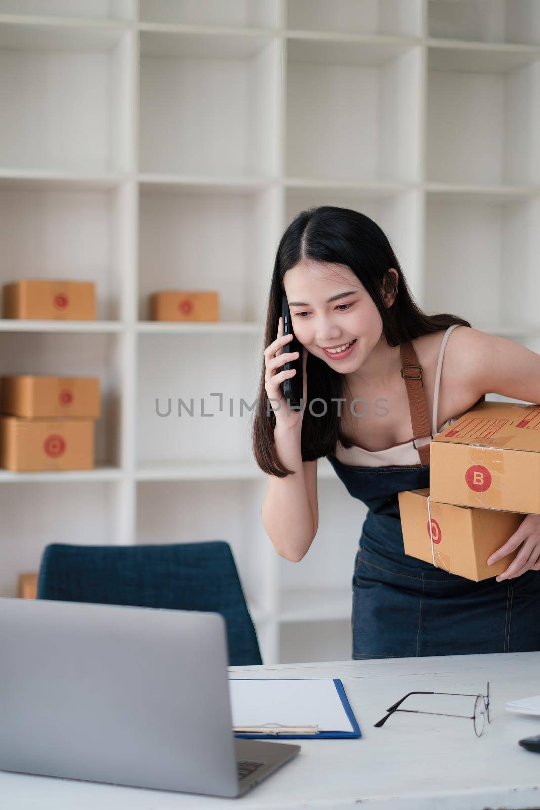 Business owner confirm address to send to customer orders talking by cell phone before pack products. Successful SME entrepreneur concept. by itchaznong