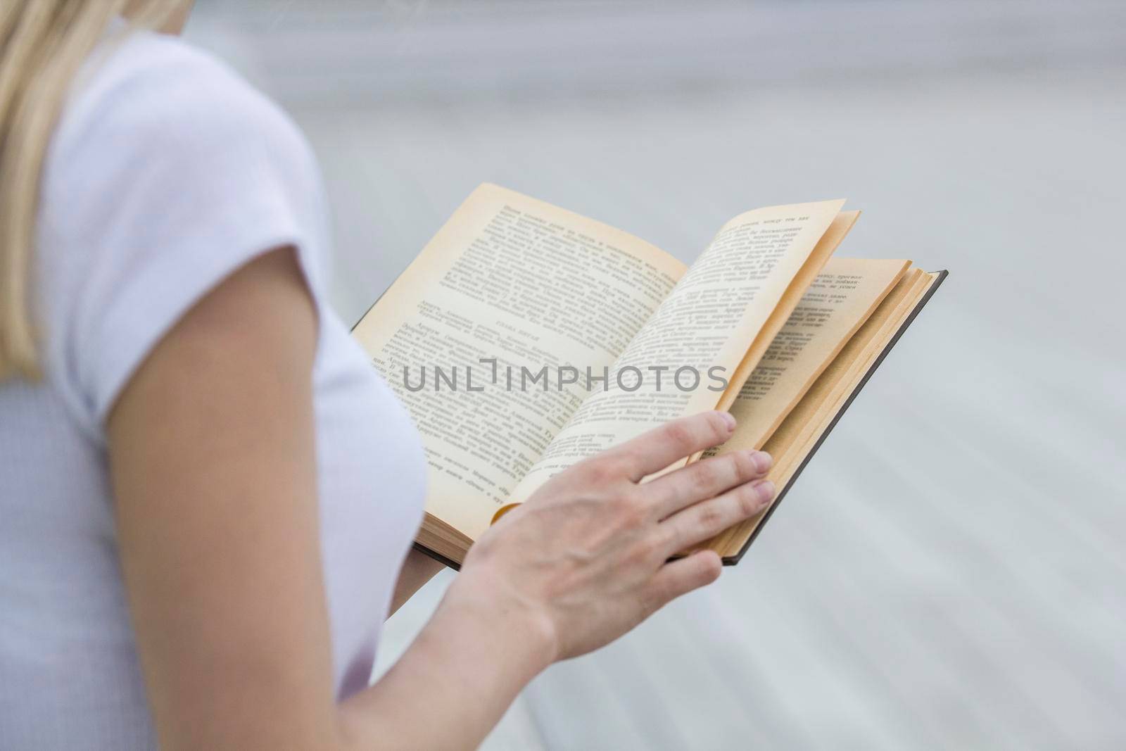 Young female hand holding an old book - reading outdoors, close up