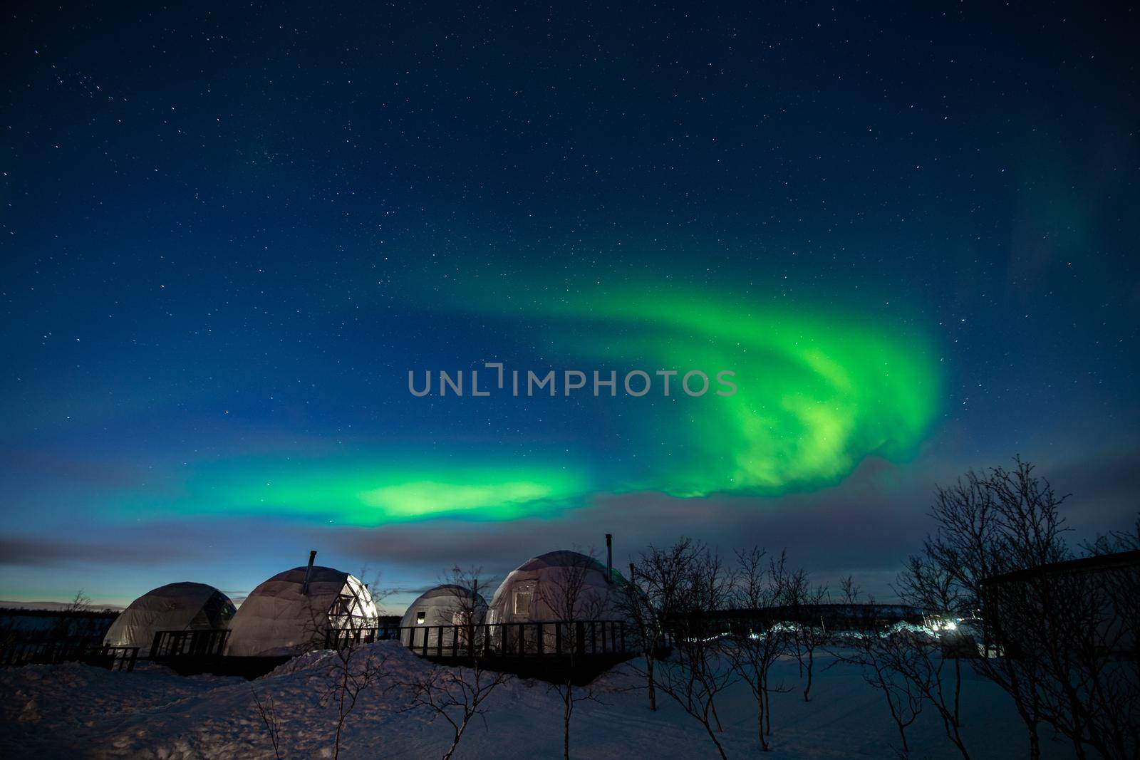 Northern Lights also known as aurora, borealis or polar lights at cold night over igloo village. Beautiful night photo of magic nature of Teriberka, Murmansk. High quality photo