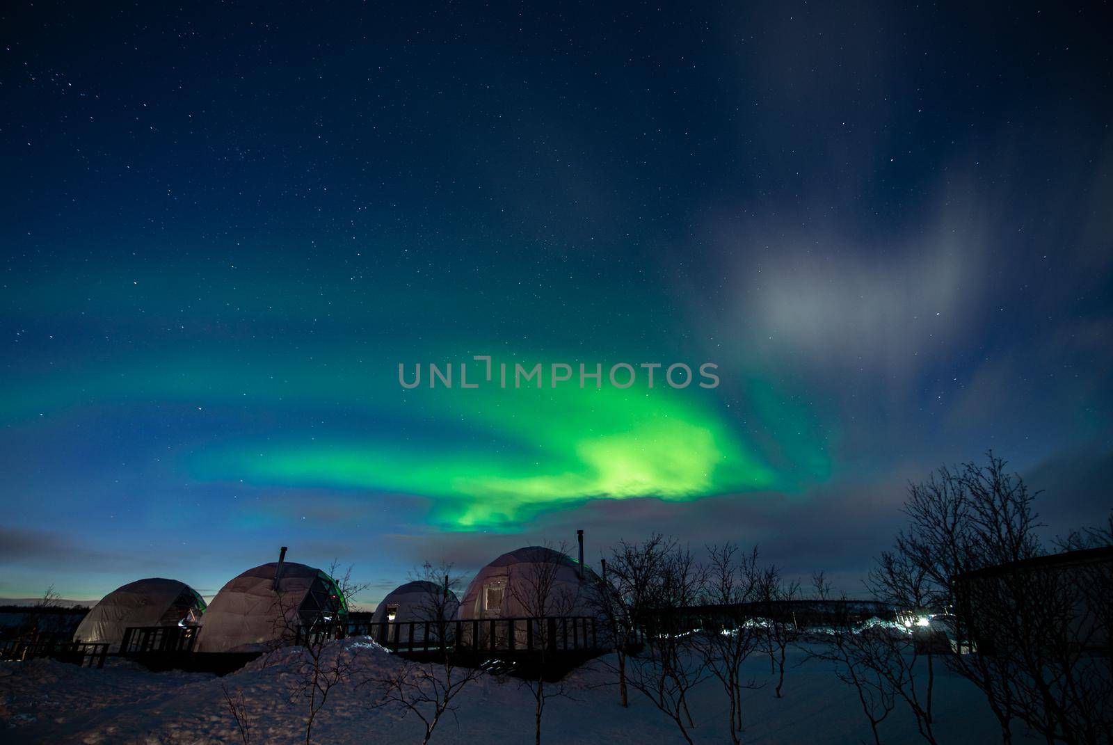 Northern Lights also known as aurora, borealis or polar lights at cold night over igloo village. Beautiful night photo of magic nature of Teriberka, Murmansk. High quality photo