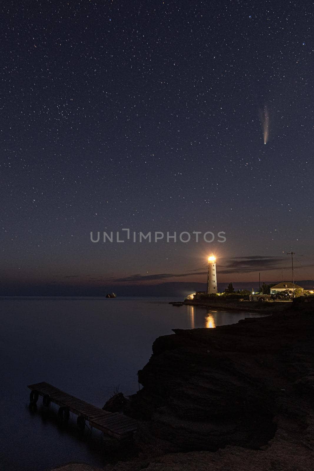 Vertical HDR Landscape of Neowise comet over white Lighthouse on starry sky by MKolesnikov