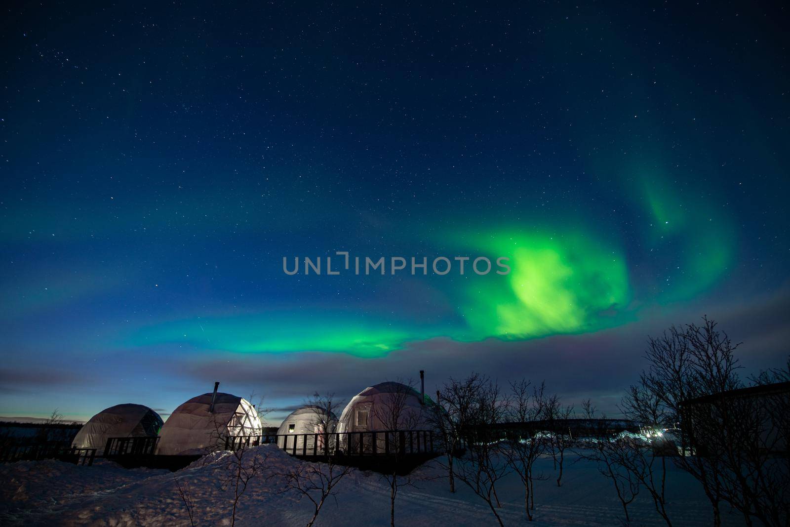 Northern Lights also known as aurora, borealis or polar lights at cold night over igloo village. Beautiful night photo of magic nature of Teriberka, Murmansk. High quality photo