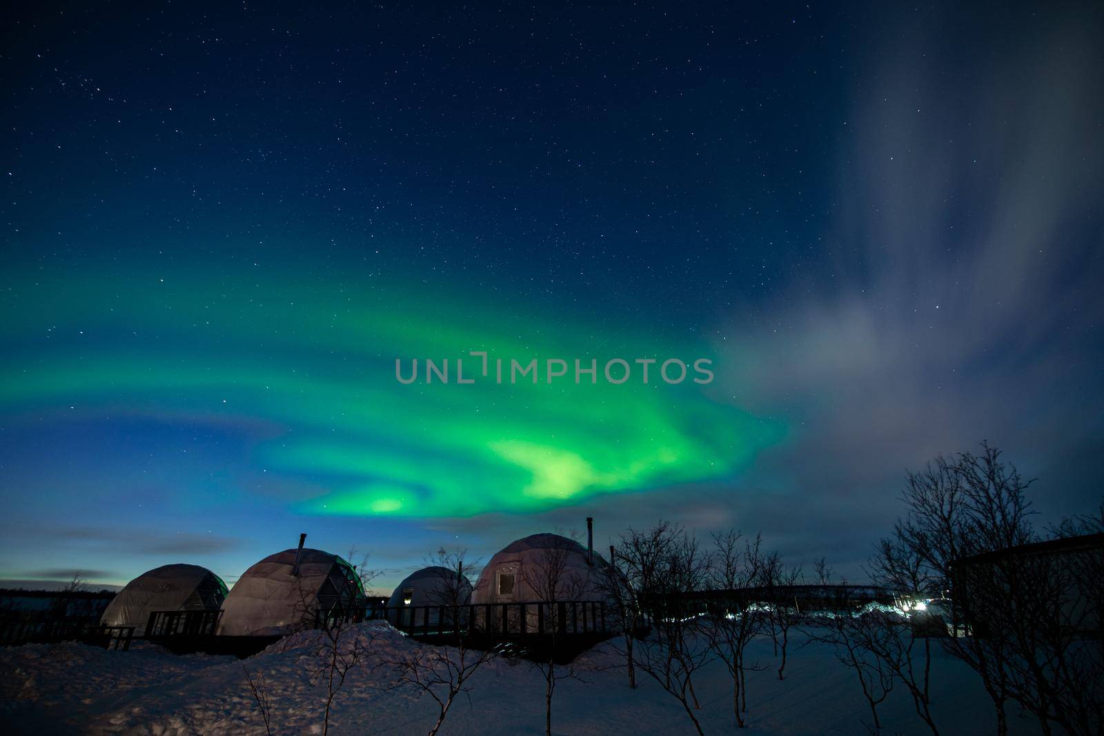 Northern Lights also known as aurora, borealis or polar lights at cold night over igloo village. Beautiful night photo of magic nature of Teriberka, Murmansk. High quality photo