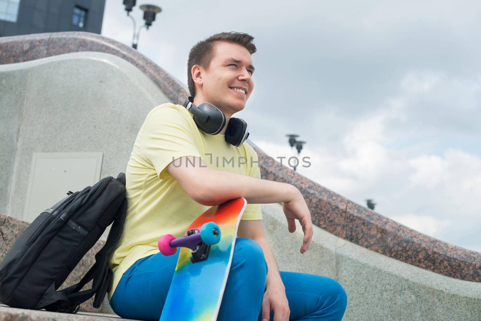 Urban young man with skateboard sitting on stair steps