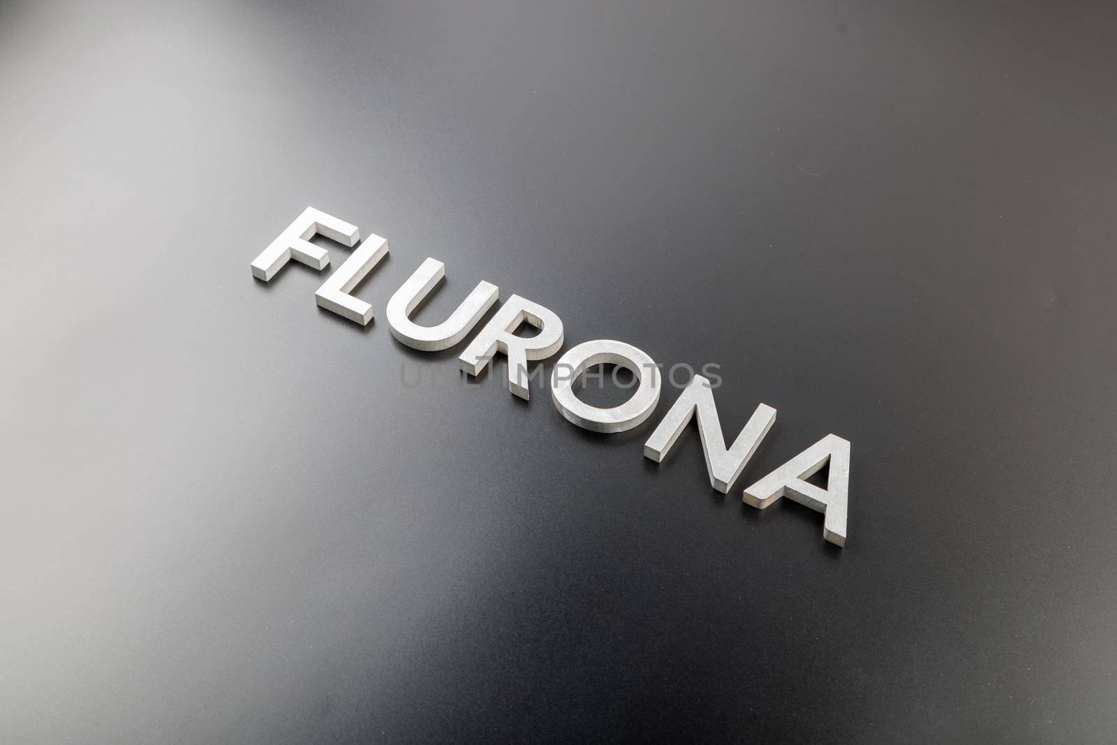 the word flurona laid with silver metal letters on gloss black background, real life photo for flu plus covid concept in diagonal perspective view
