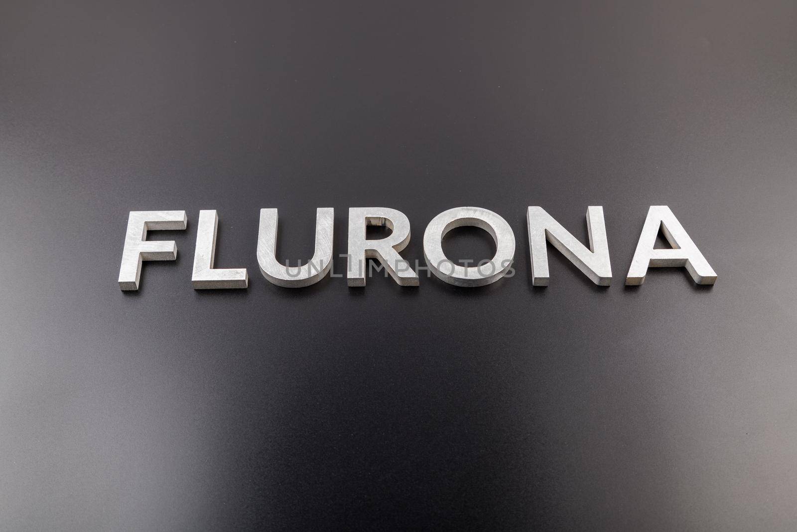 the word flurona laid with silver metal letters on gloss black background, real life photo for flu plus covid concept in frontal perspective view