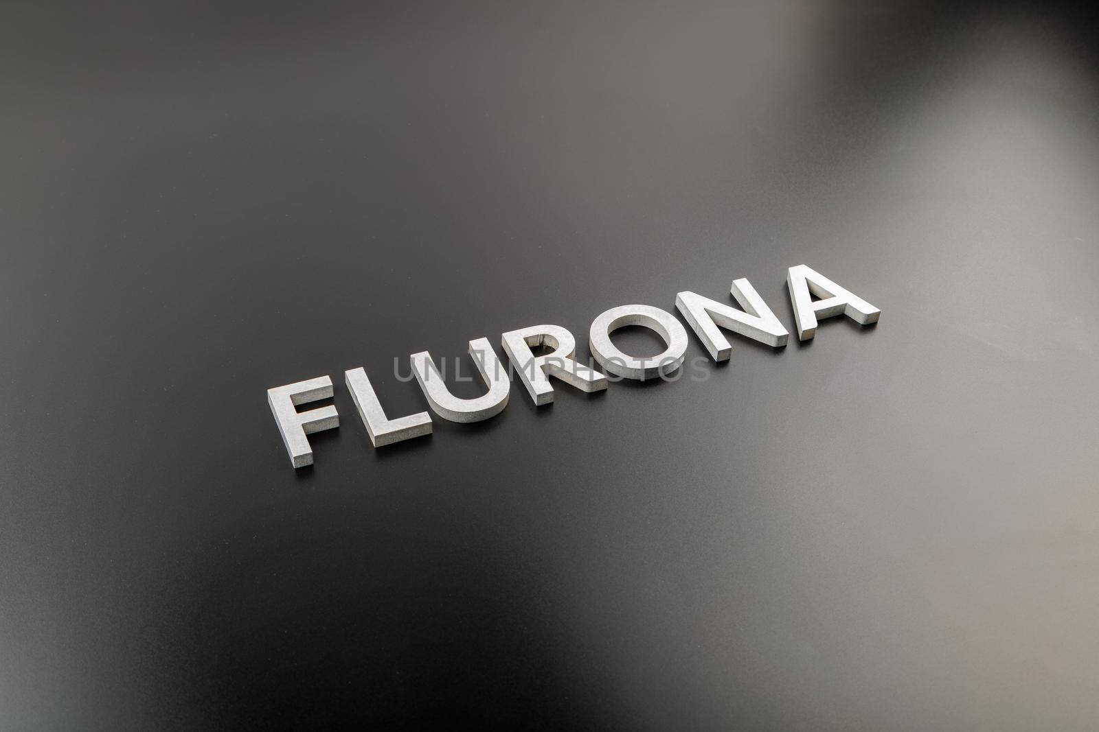 the word flurona laid with silver metal letters on gloss black background, real life photo for flu plus covid concept in diagonal perspective view