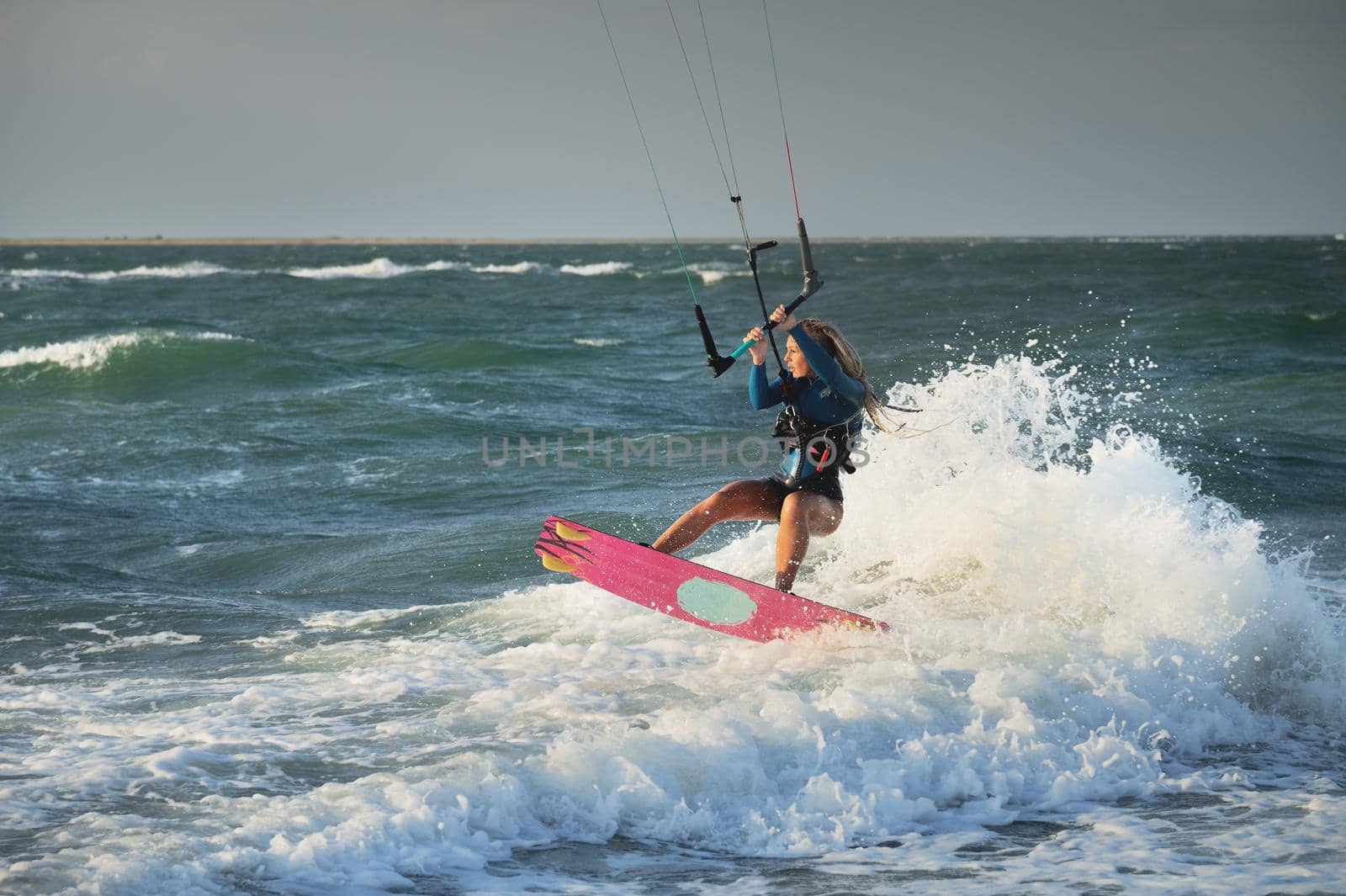Professional kitesurfer caucasian woman rides big waves in windy weather. Kitesurfing by yanik88