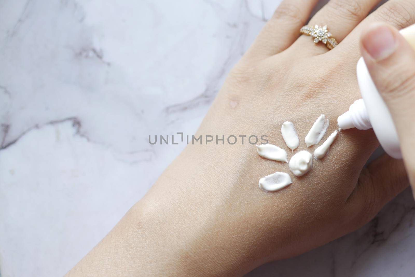 women applying sunscreen cream on hand .