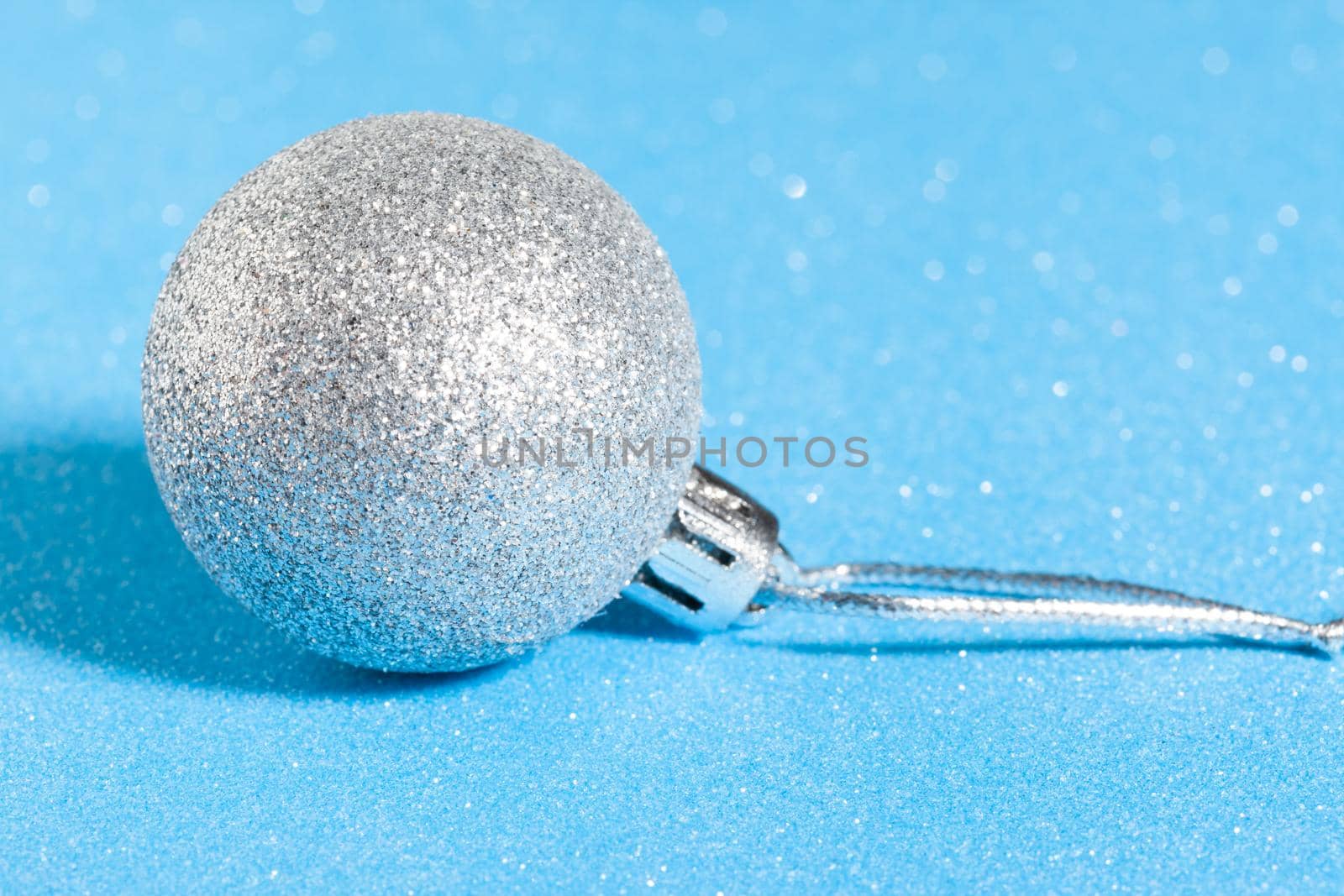 silver shiny christmas ball on sparkling blue background.