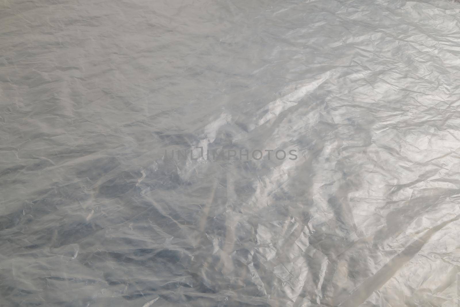 full frame background of flat crumpled semi-transparent polyethylene film.