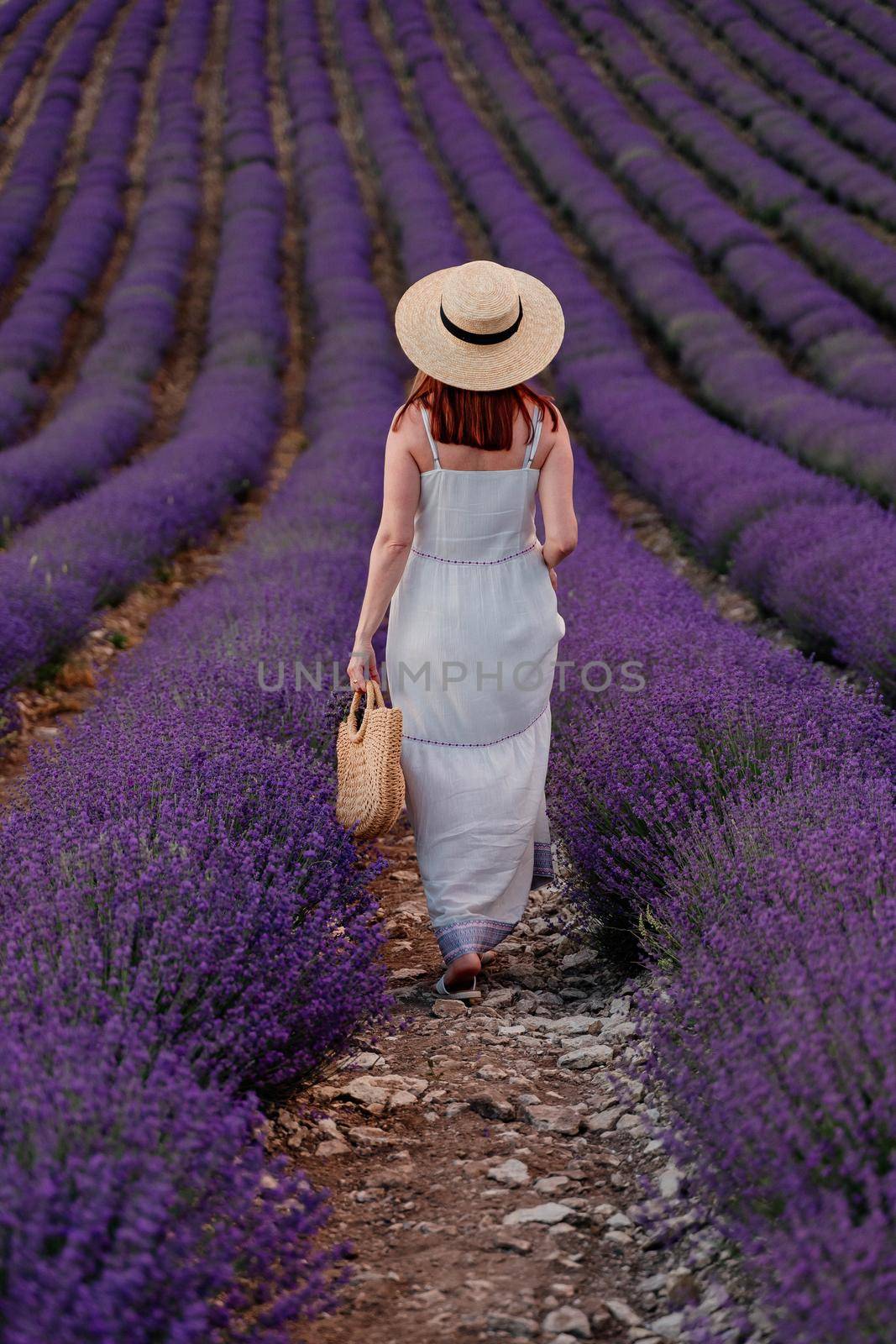 charming Young woman with a hat and white dress in a purple lavender field. LIfestyle outdoors. Back view by Matiunina