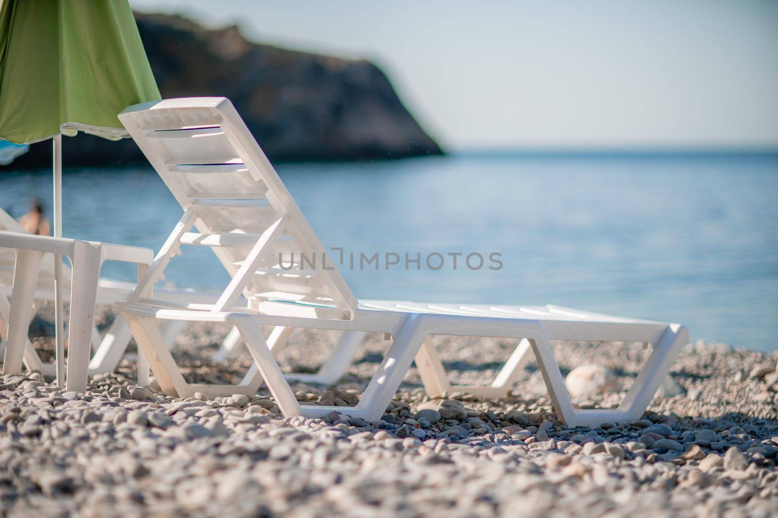 white sun loungers and an umbrella on a deserted beach. The perfect vacation concept. by Matiunina