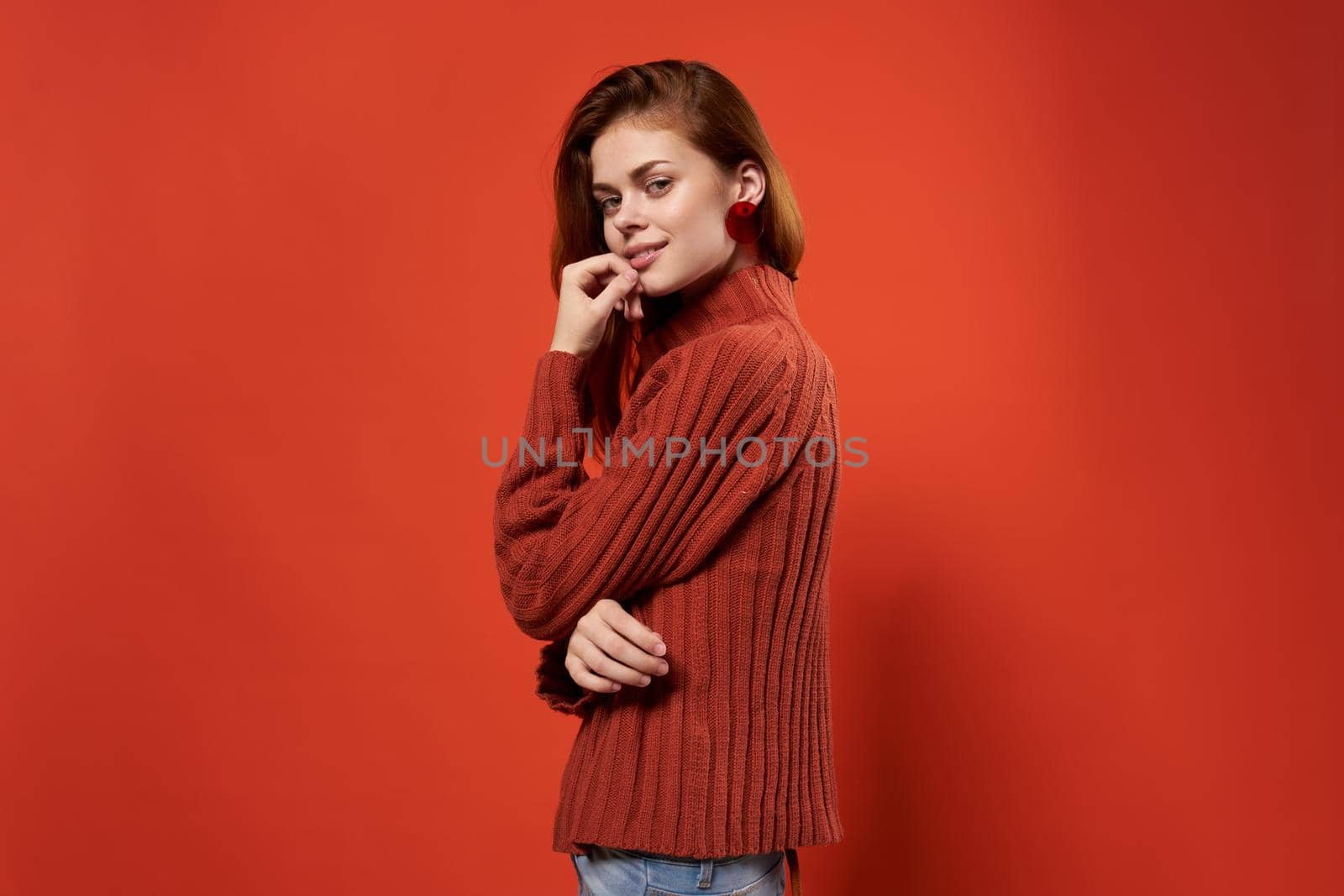 cheerful woman in a red sweater makeup earrings fashion studio. High quality photo