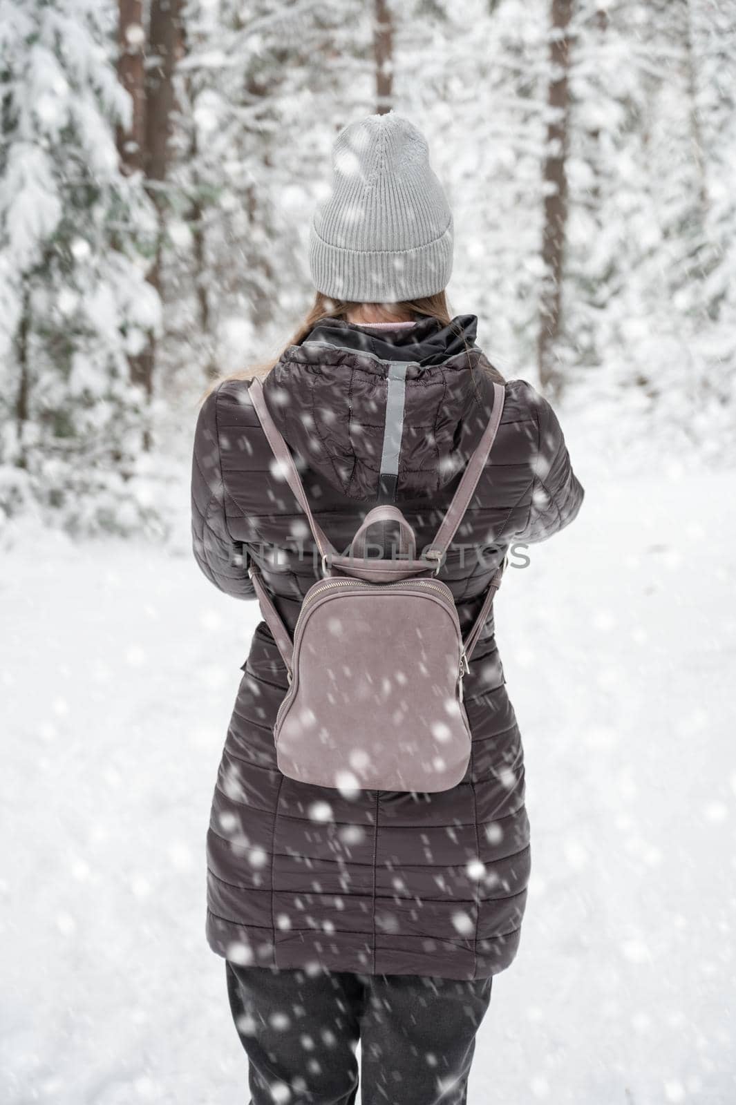 Woman in winter jacket walking in snowy winter forest, snowy winter day