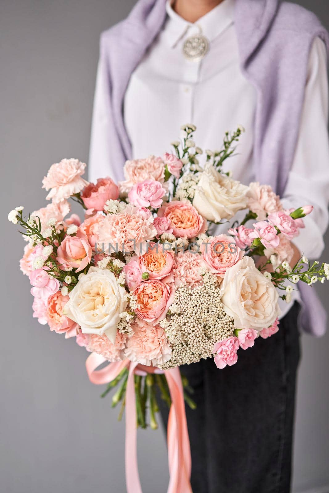 Flower arrangement in Wicker basket. Beautiful bouquet of mixed flowers in woman hand. Handsome fresh bouquet. Small flower shop and Flowers delivery