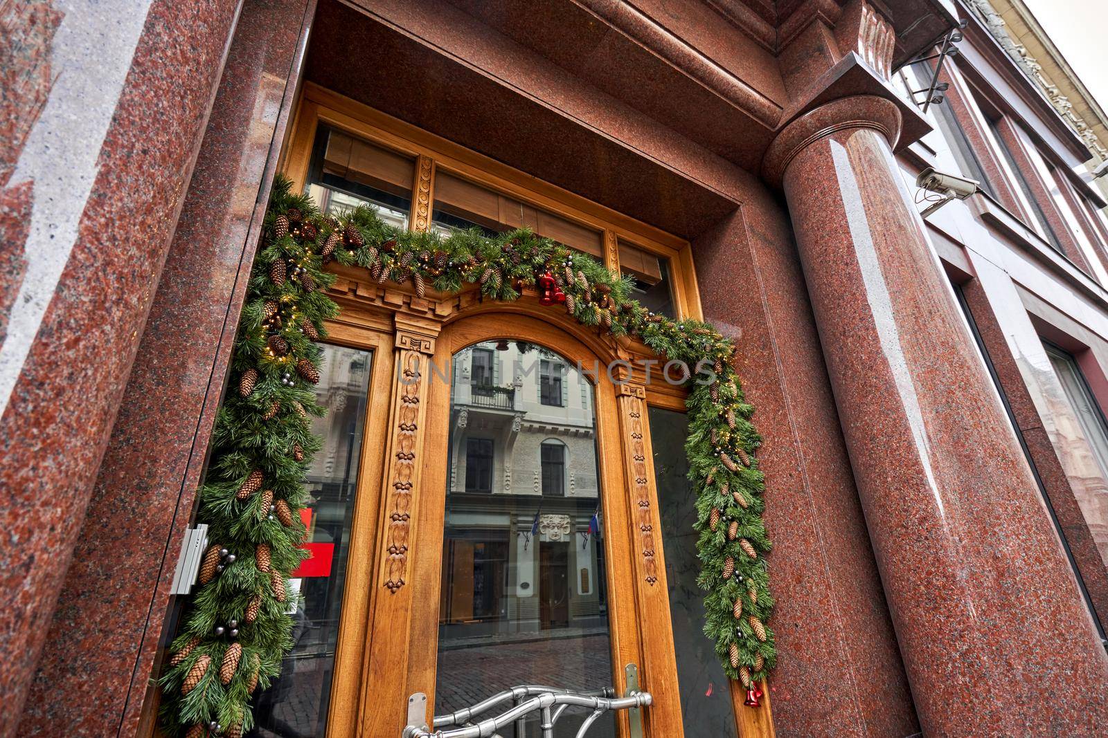 Christmas morning. House with a decorated door with a Christmas wreath and tree branches. Street european city