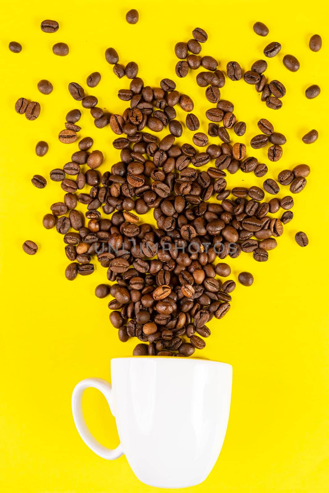 coffee beans come out of a cup in front of a yellow background
