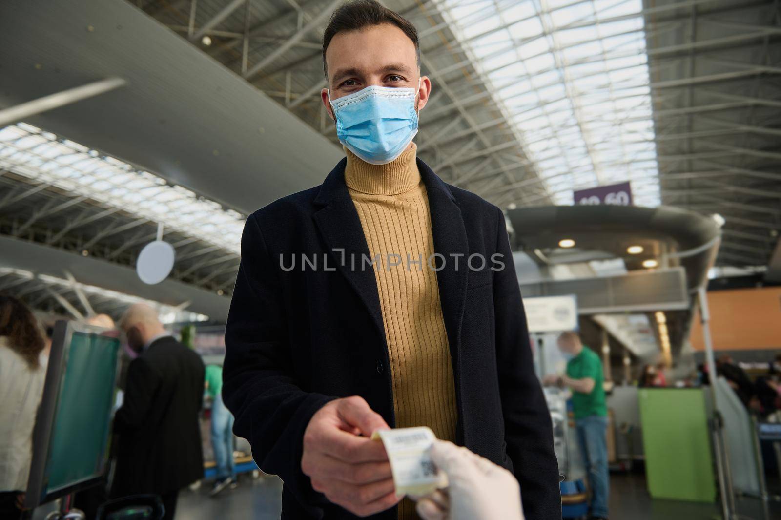 Handsome young man in a protective medical mask receives a QR code after being tested before departure at the international airport. Safe flight and travel during a pandemic by artgf