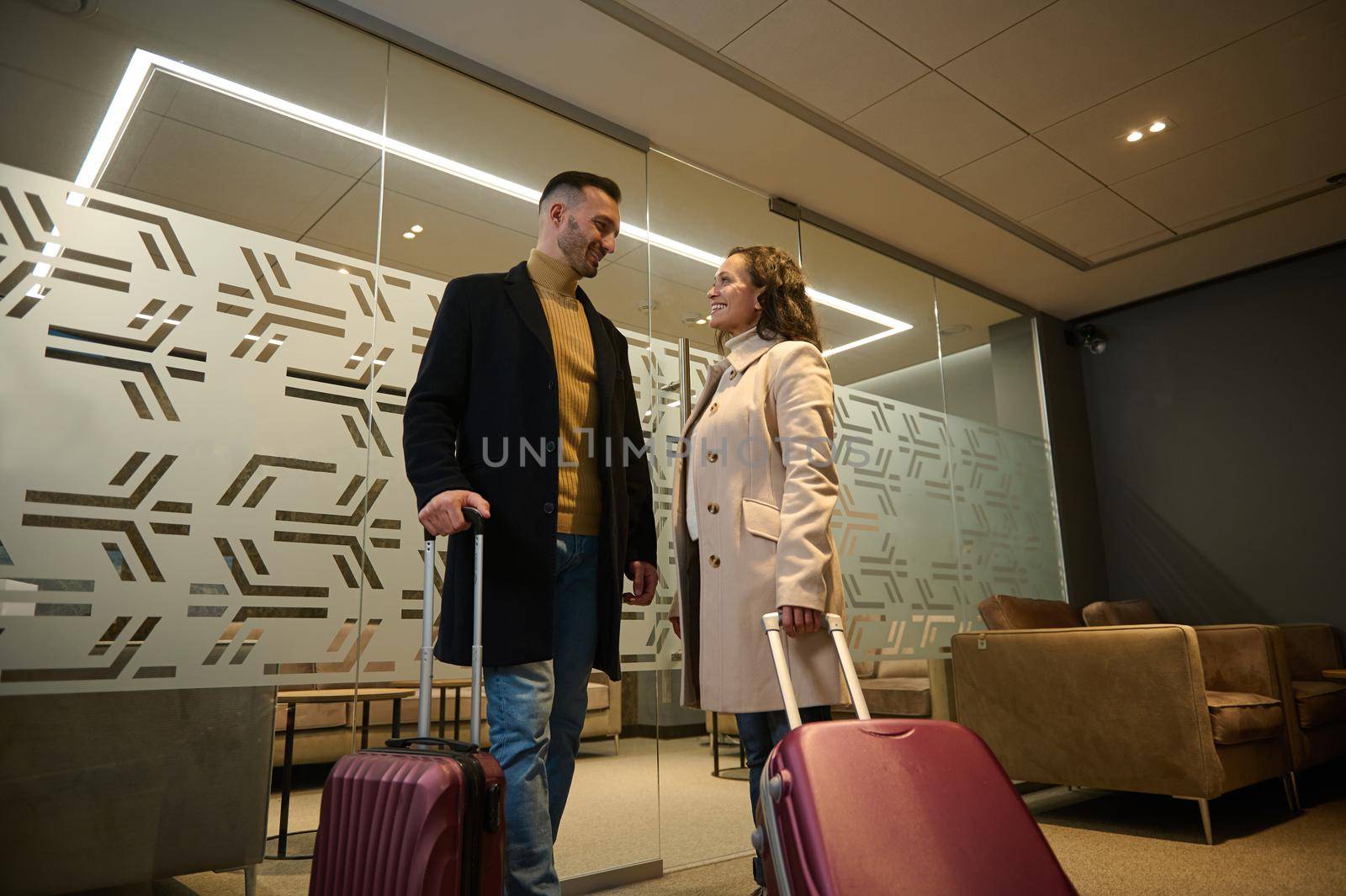 Multi ethnic beautiful couple in love, business partners on business trip, standing at the exit of VIP meeting room in the airport departure terminal, waiting for flight. Newlyweds on their honeymoon by artgf