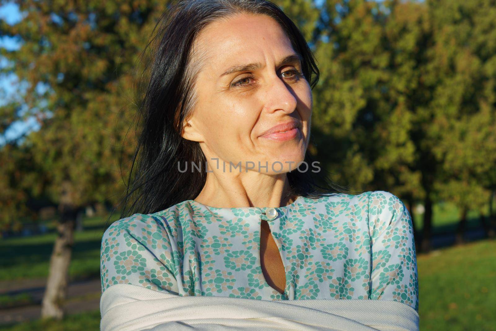 Profile side view portrait of attractive cheerful dreamy grey-haired middle-aged woman relaxing outdoors during sunny day.