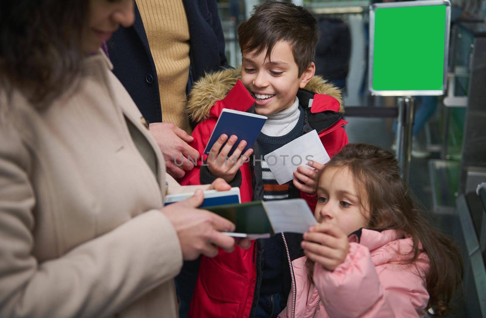 Cheerful children enjoying family travel, giving passports to their mother while passing passport and customs control in the airport. Air travel journey concept