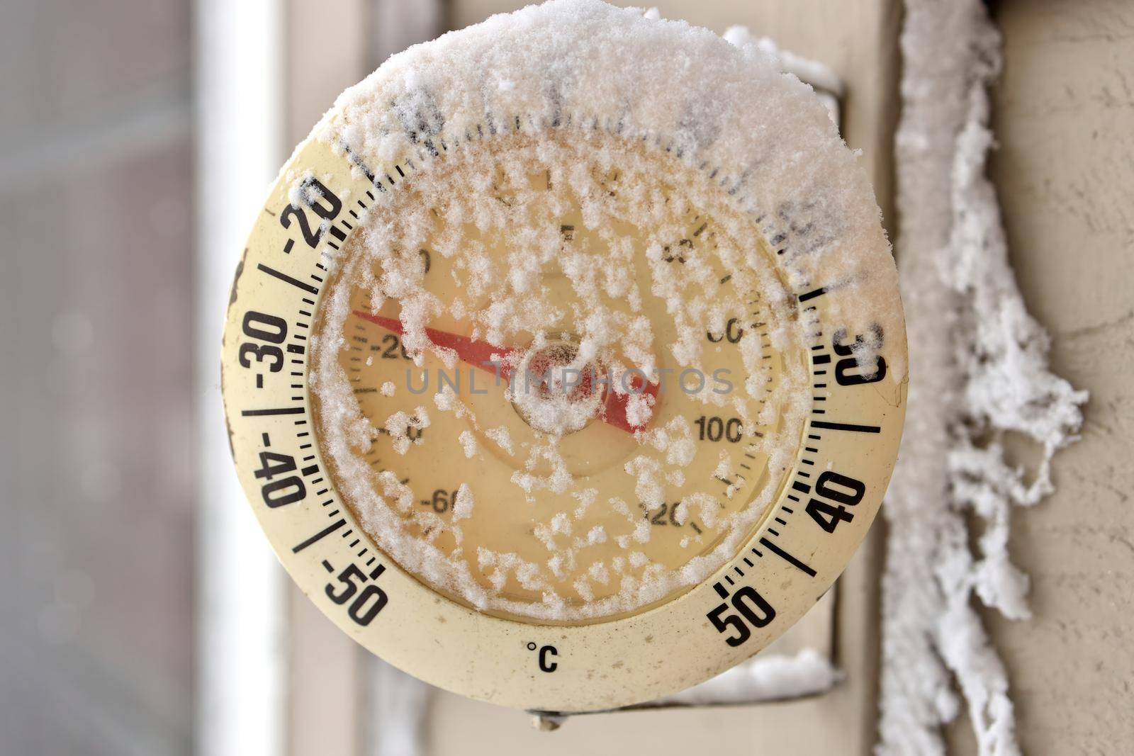Close up of a Frosty snow-capped outdoor Thermometer on a frigid cold winter day. Temperature reads minus 26 degrees Celsius or minus 16 Fahrenheit