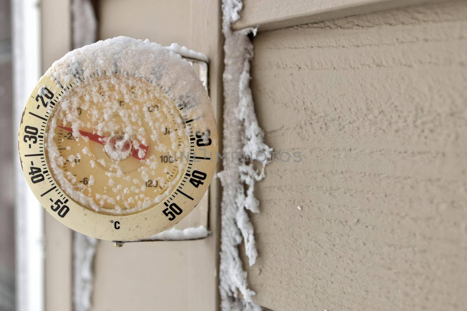 Close up of a Frosty snow-capped outdoor Thermometer on a frigid cold winter day. Temperature reads minus 26 degrees Celsius or minus 16 Fahrenheit