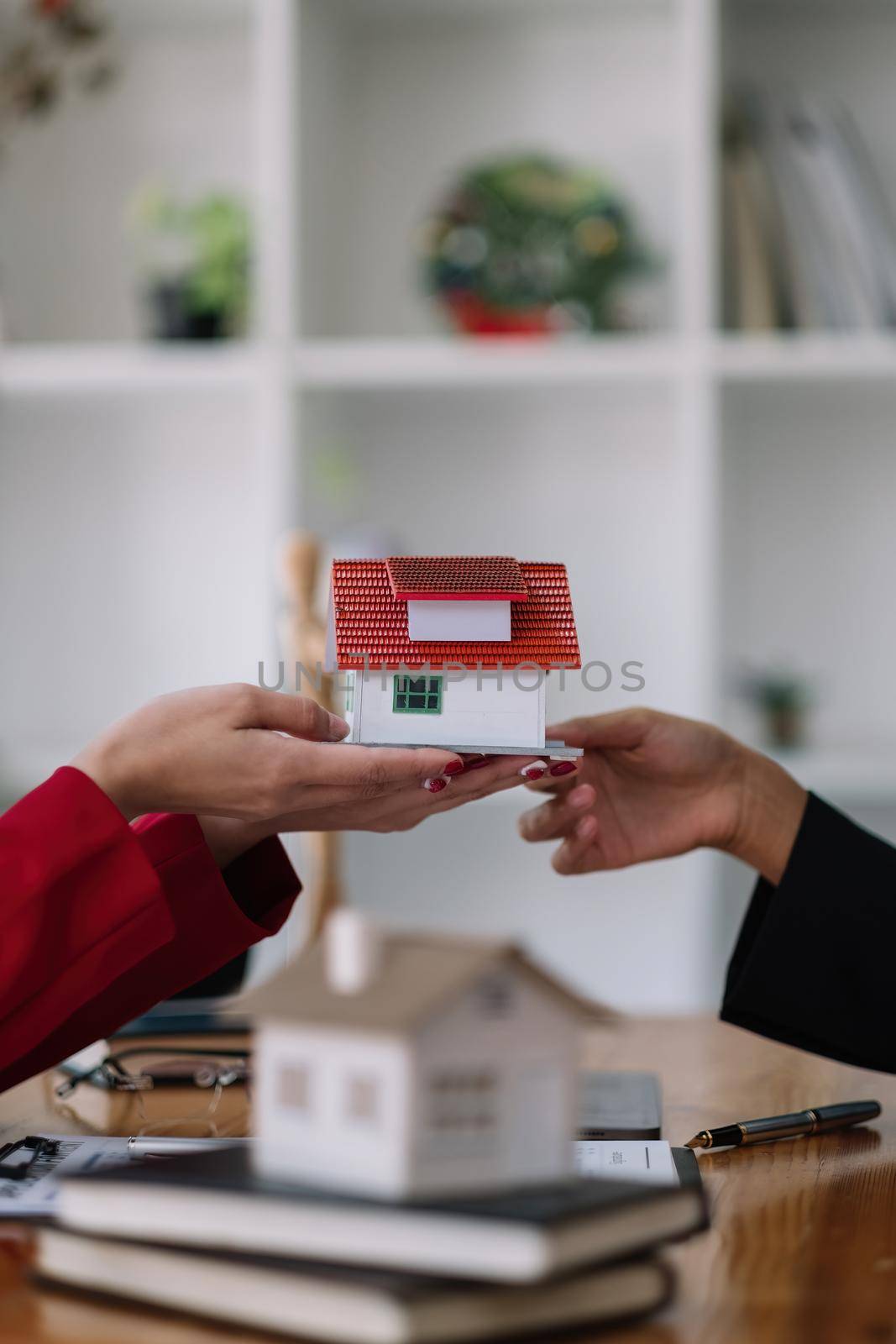 Real estate agent sales manager holding house model to customer after signing rental lease contract of sale purchase agreement, concerning mortgage loan offer for and house insurance.