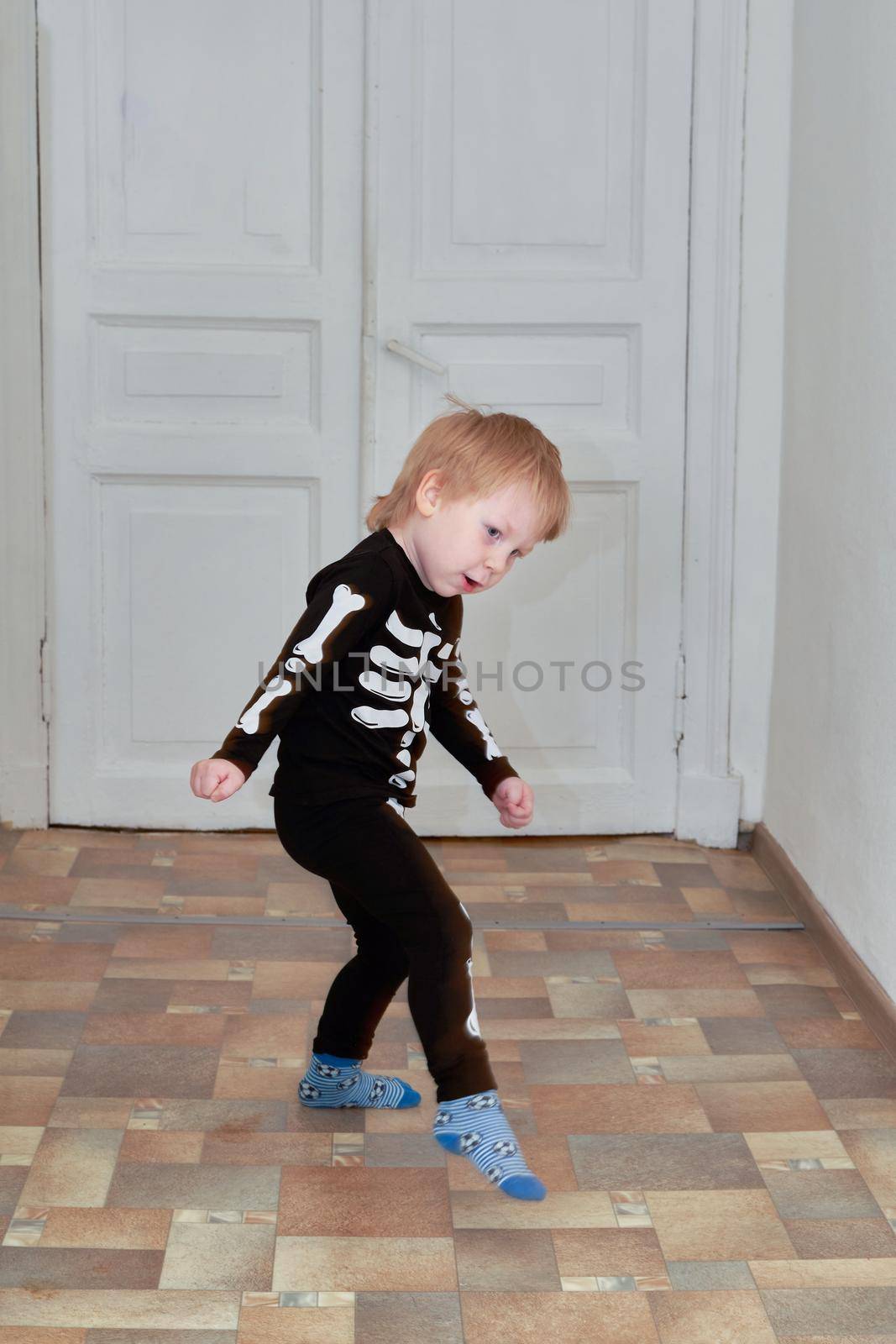 A child in a skeleton costume is dancing in the hallway of the house. Children outdoor games at home