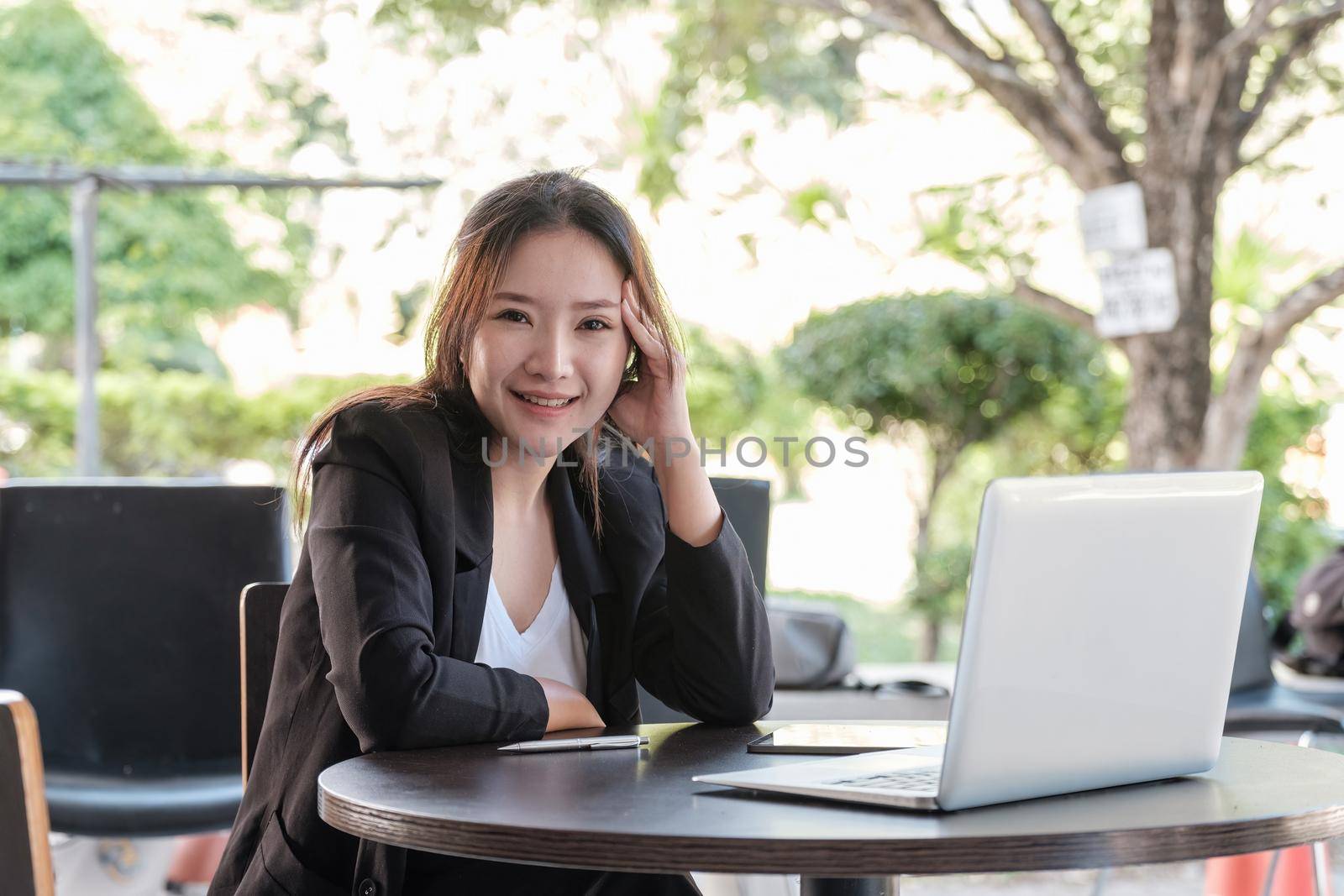 Portrait charming asian businesswoman sitting working on laptop in office. looking on camera.