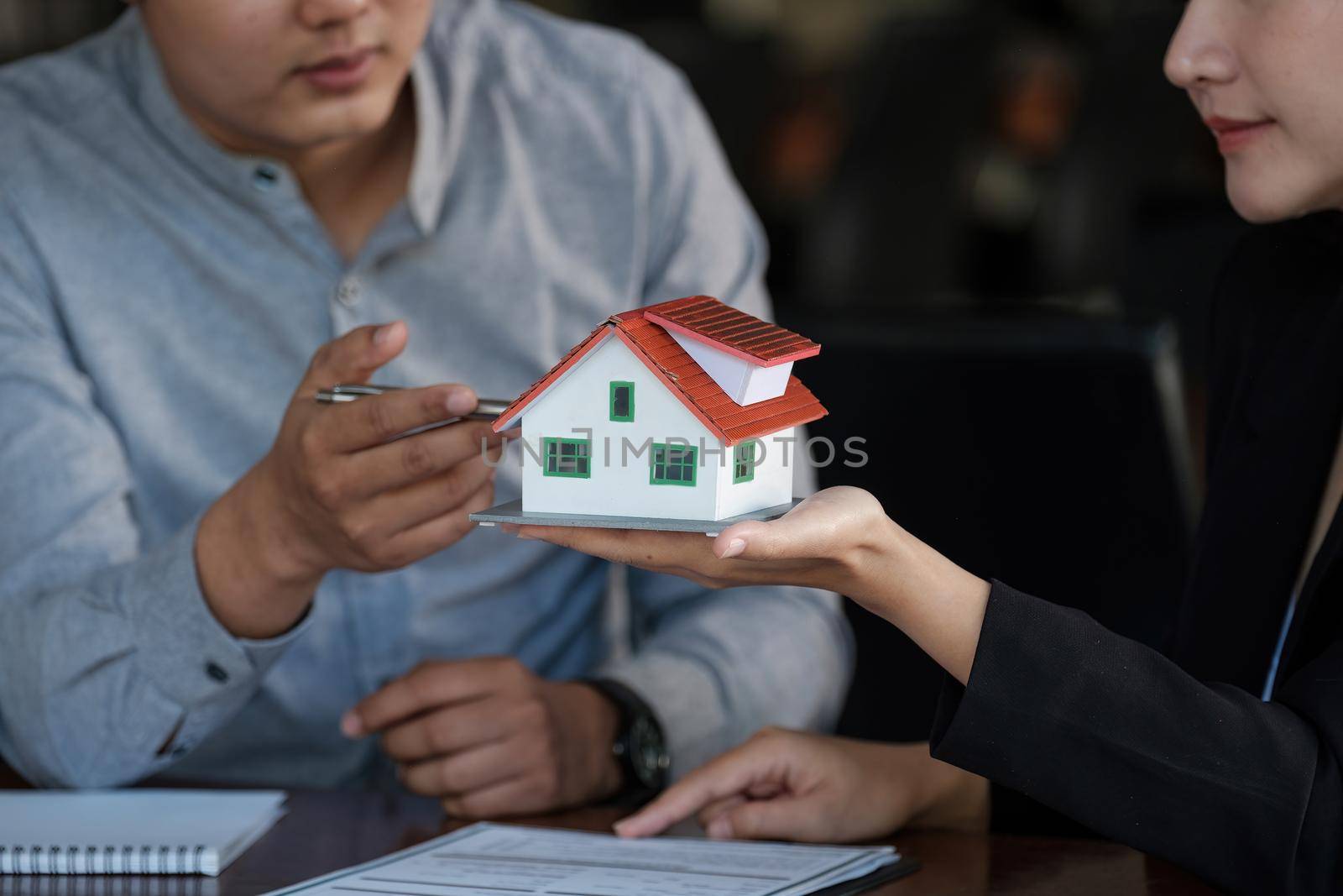 Real estate agent sales manager holding house model to customer after signing rental lease contract of sale purchase agreement, concerning mortgage loan offer for and house insurance.