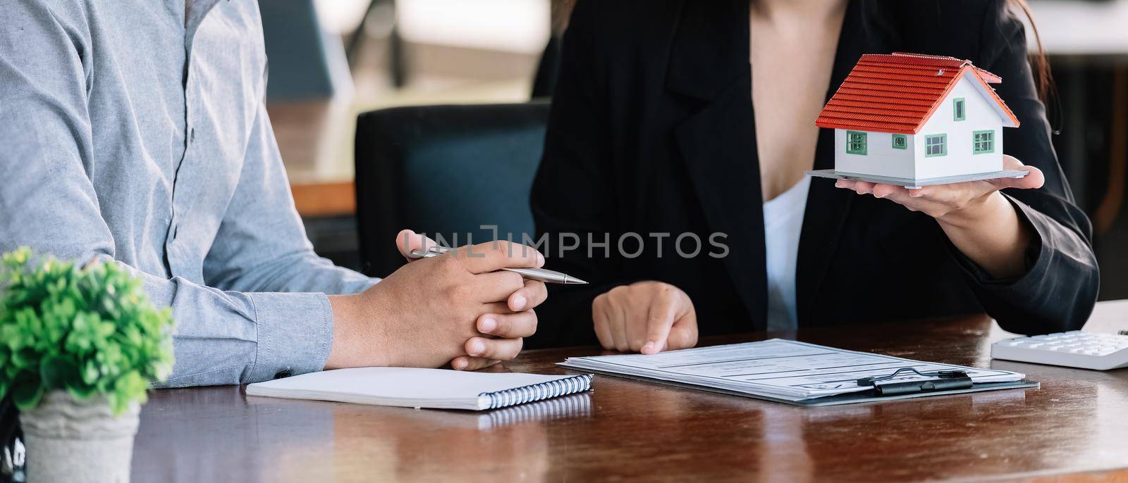 Real estate agent sales manager holding house model to customer after signing rental lease contract of sale purchase agreement, concerning mortgage loan offer for and house insurance.