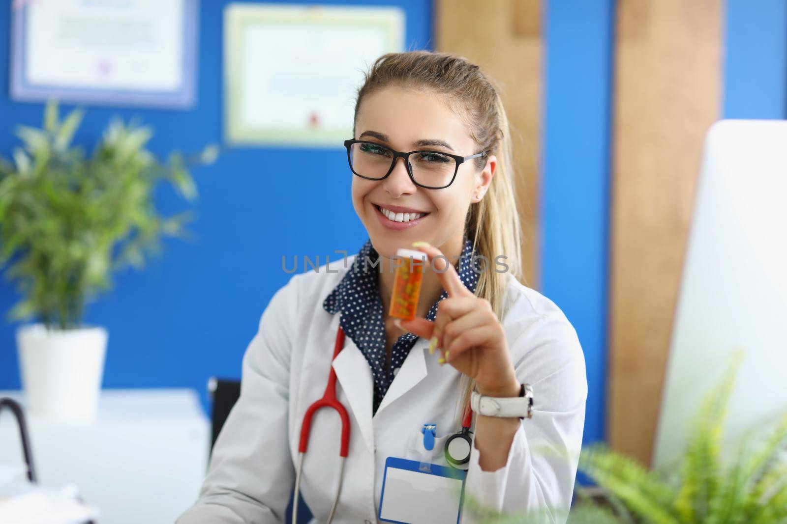 Portrait of doctor in uniform holding plastic container filled with tablets. Qualified intern advertises medication for treatment. Health, pharmacy concept
