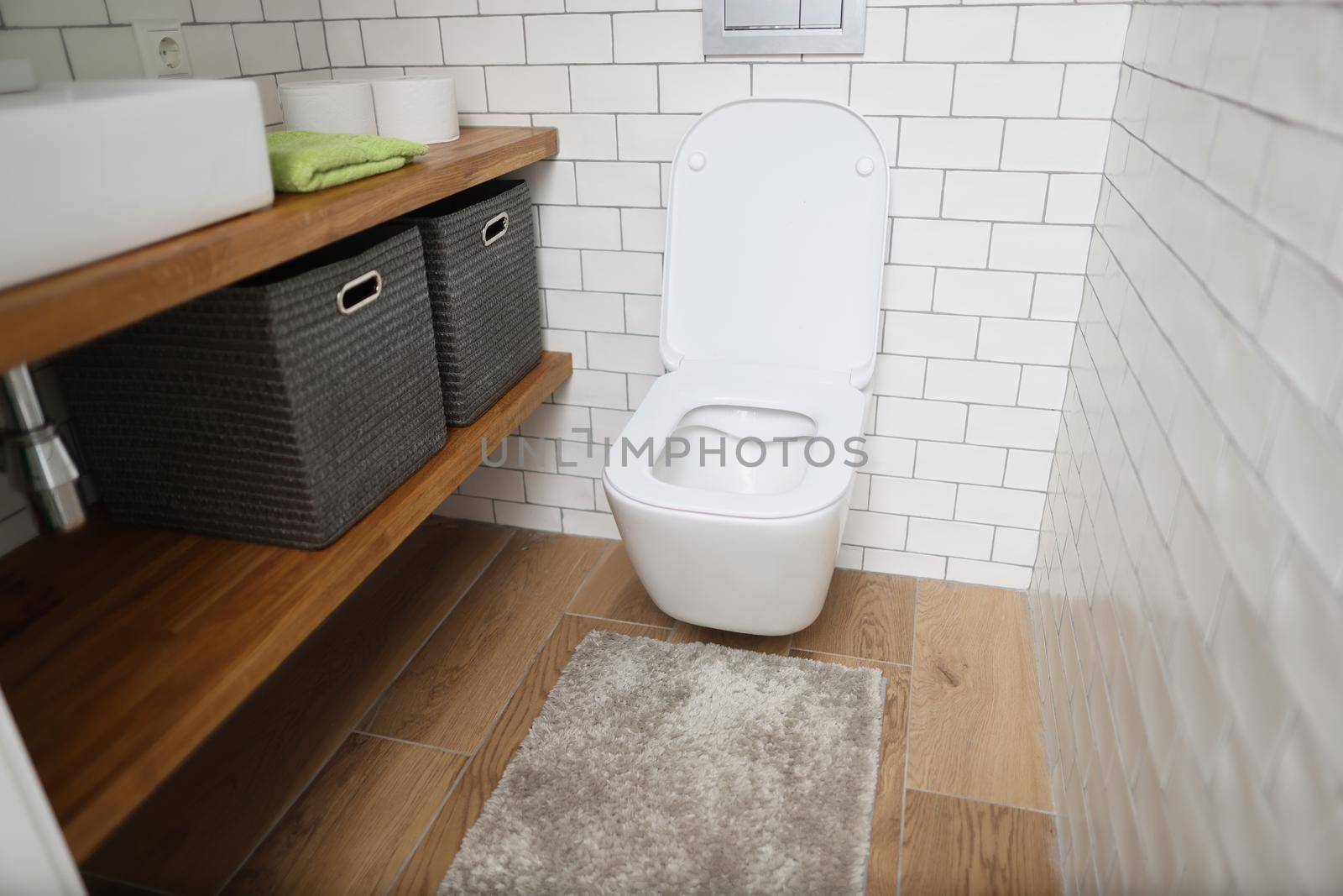 Portrait of modern bathroom interior with wooden shelves, white sink and toilet. Fresh interior, toilet paper, soap, decor. Renovation, restroom concept