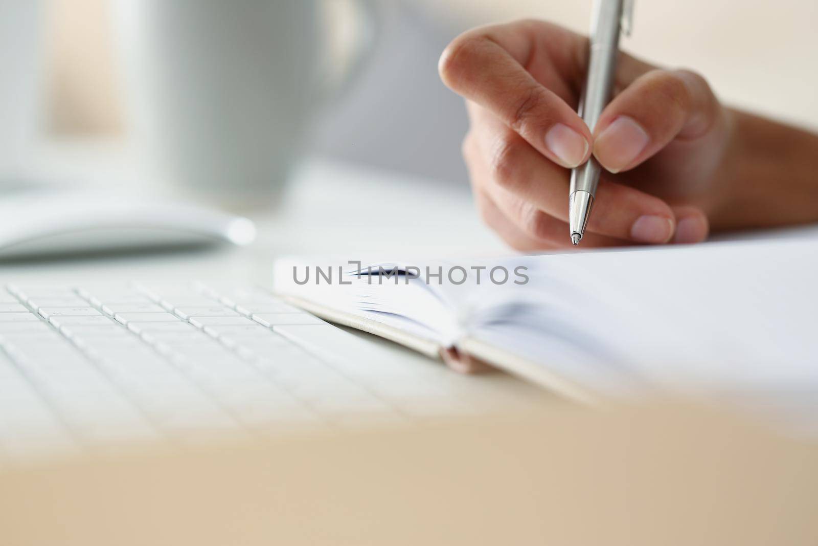 Close-up of persons hand writing down ideas in diary, notes for future, planning day in advance. Write with silver pen. Journal, creativity, writer concept