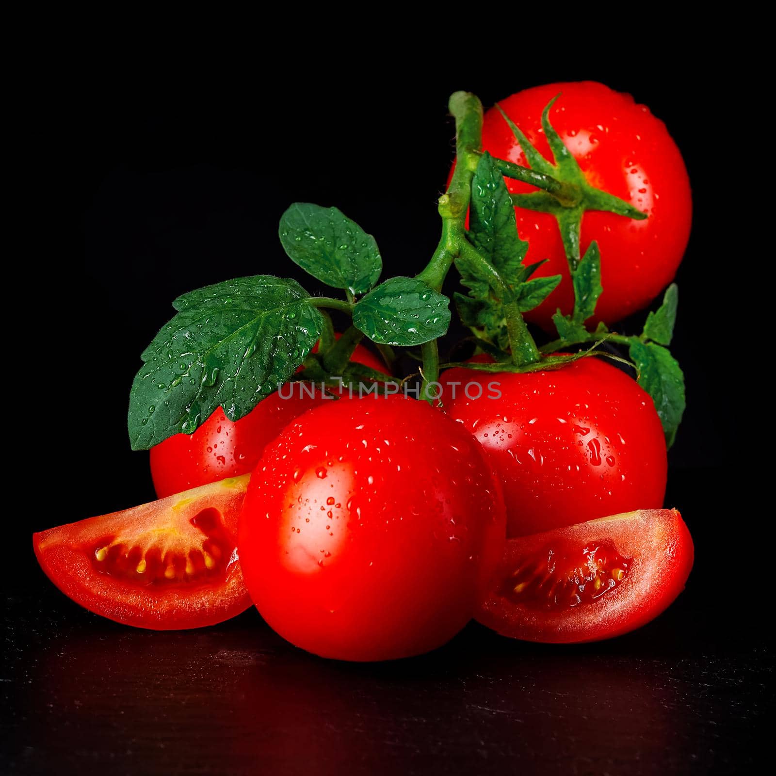 Ripe organic tomatoes on the black table in low key with water drops by PhotoTime