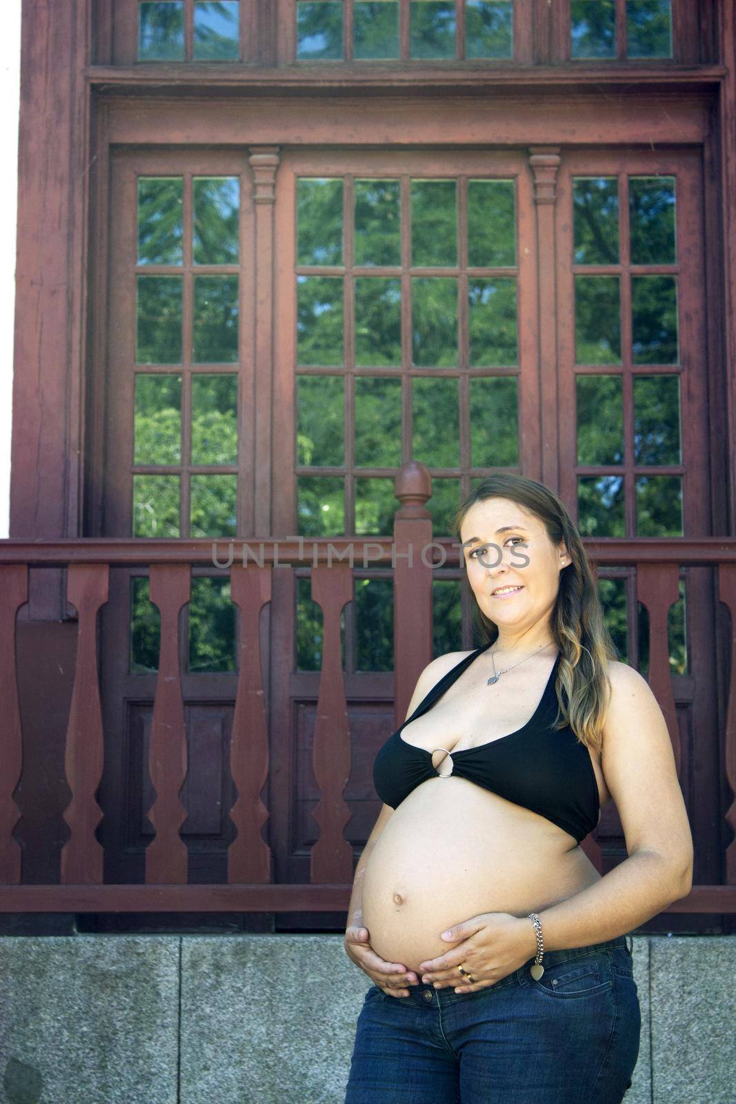 Seven months pregnant young woman dressed in black bikini and jeans