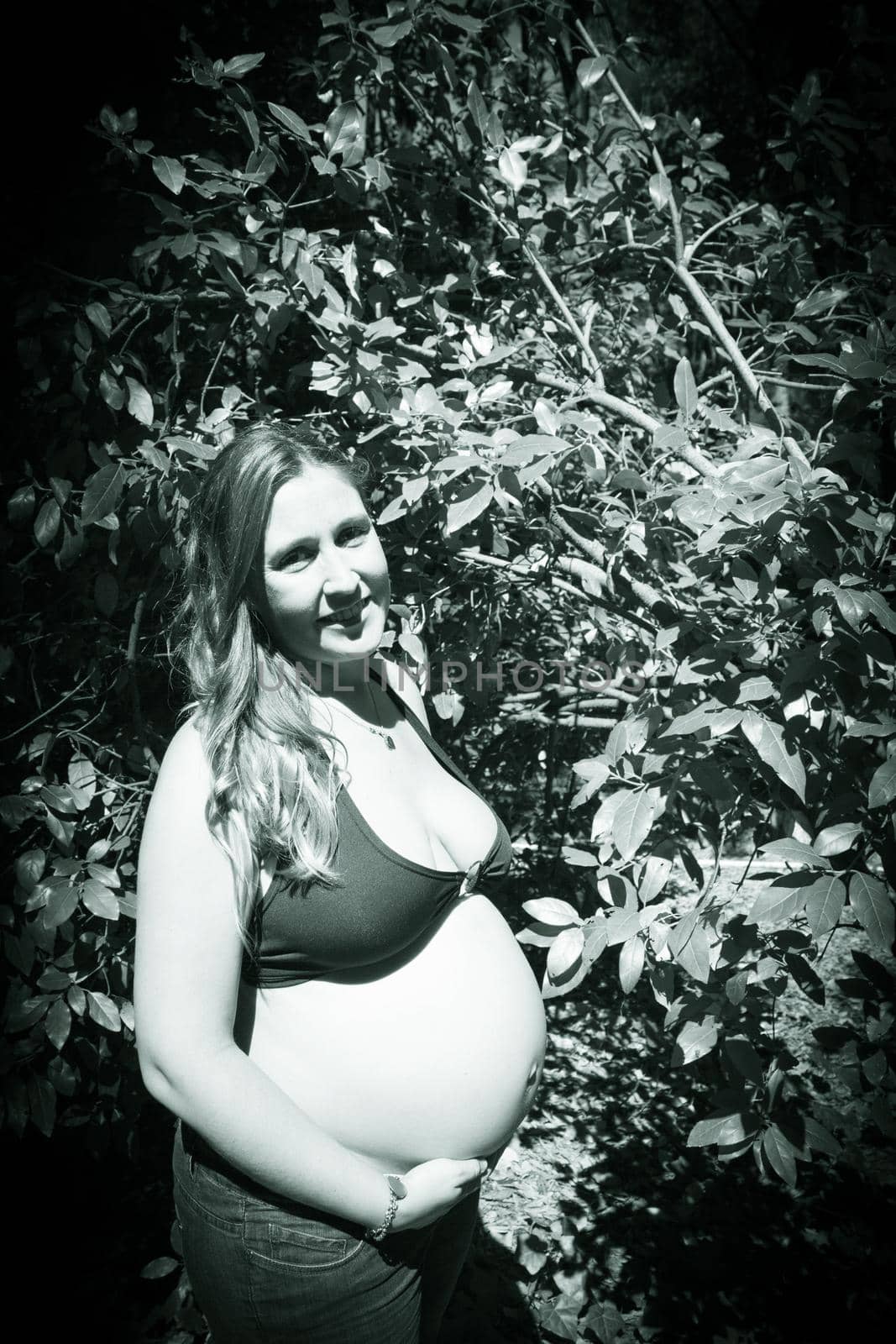 Seven month pregnant woman in a park dressed in jeans