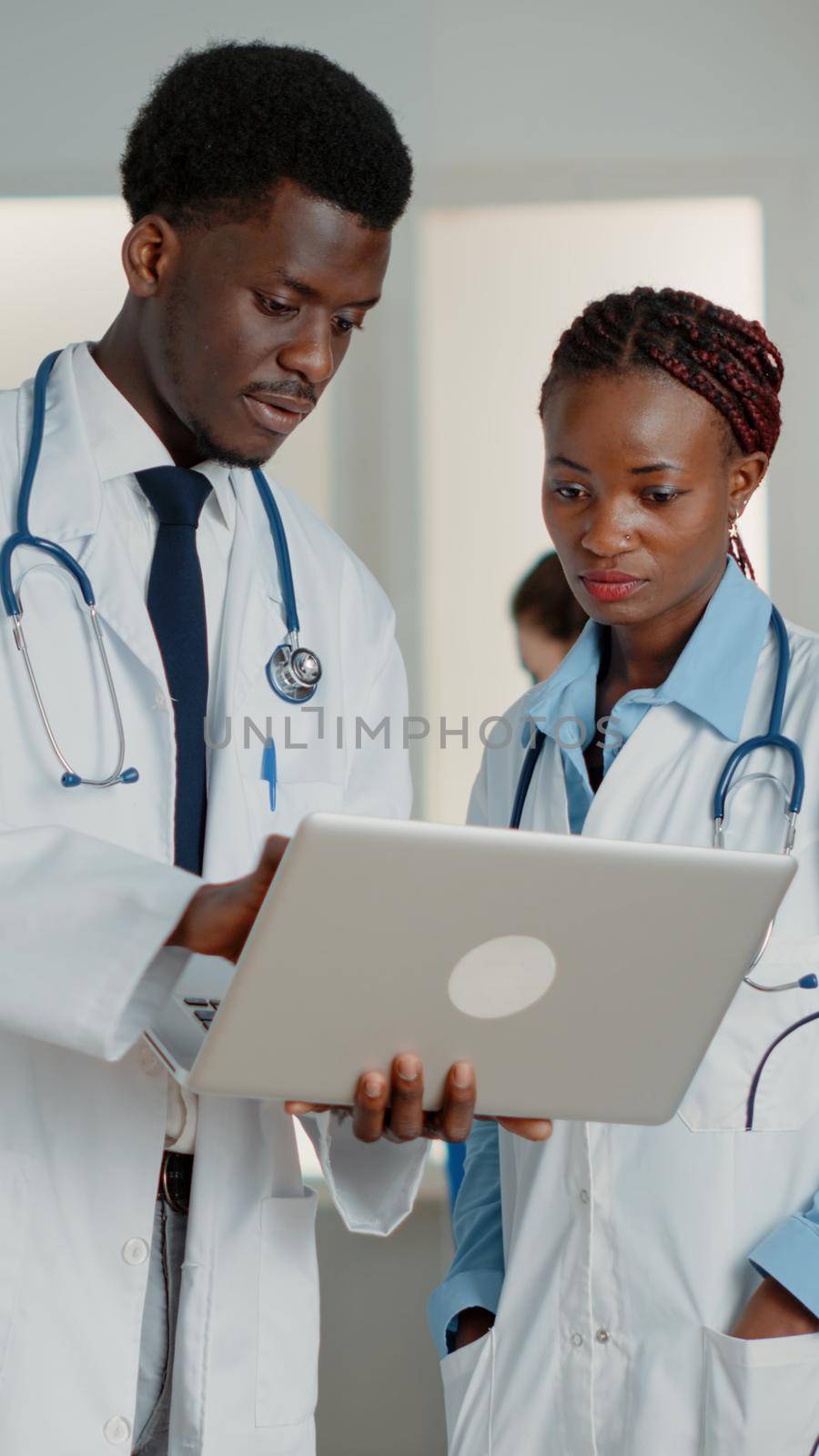 African american doctors looking at laptop to find treatment to cure patient with disease. Medical team of specialists working with device to search healthcare information in hospital ward